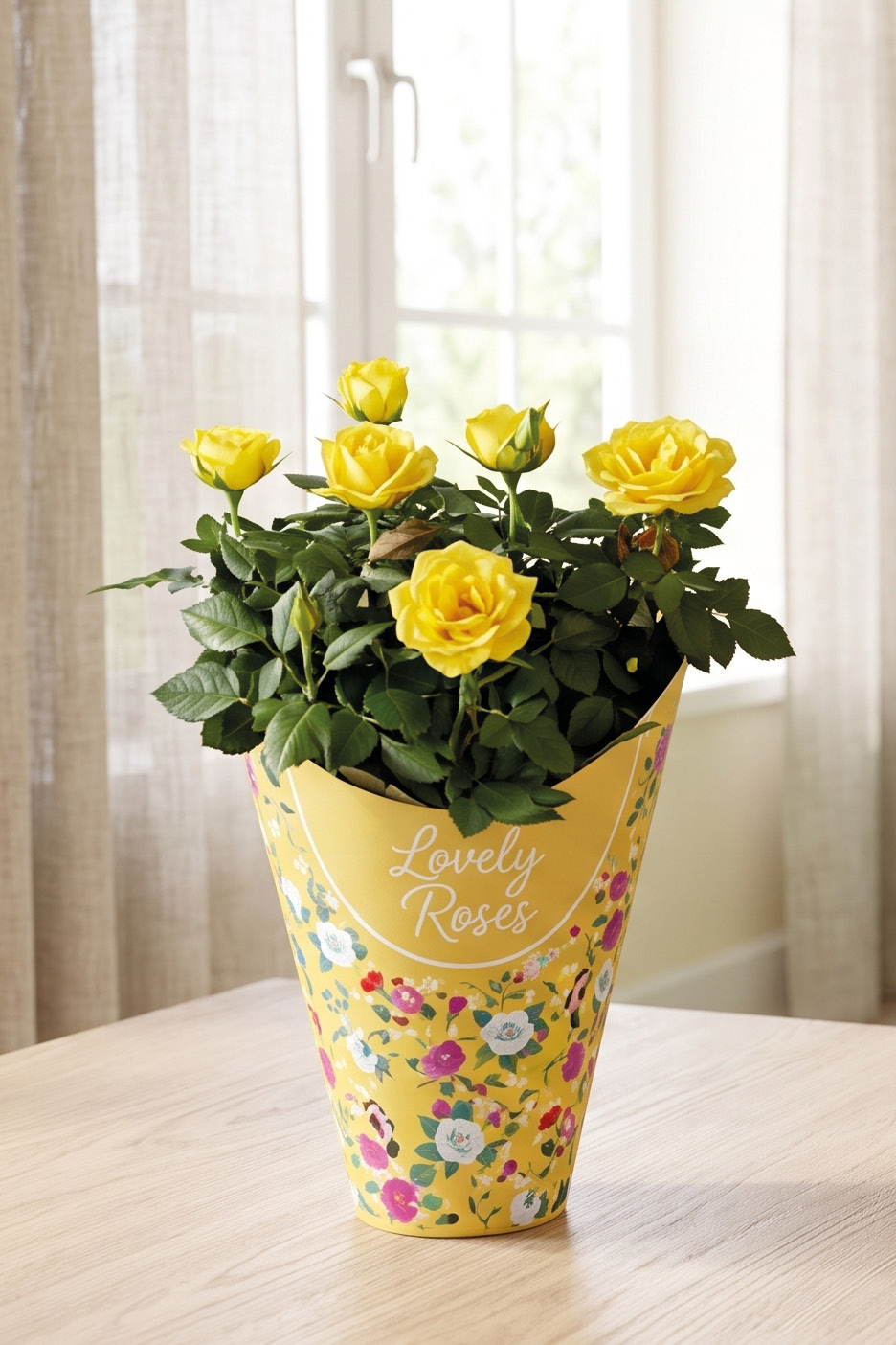 Potted yellow roses in a decorative yellow wrapper with 'Lovely Roses' text on a wooden table.