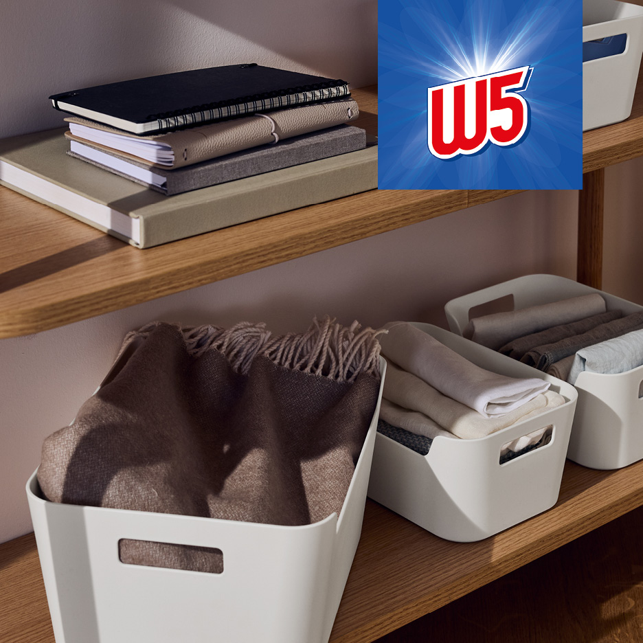 White storage bins with textiles and notebooks on wooden shelves, with a bright W5 logo.