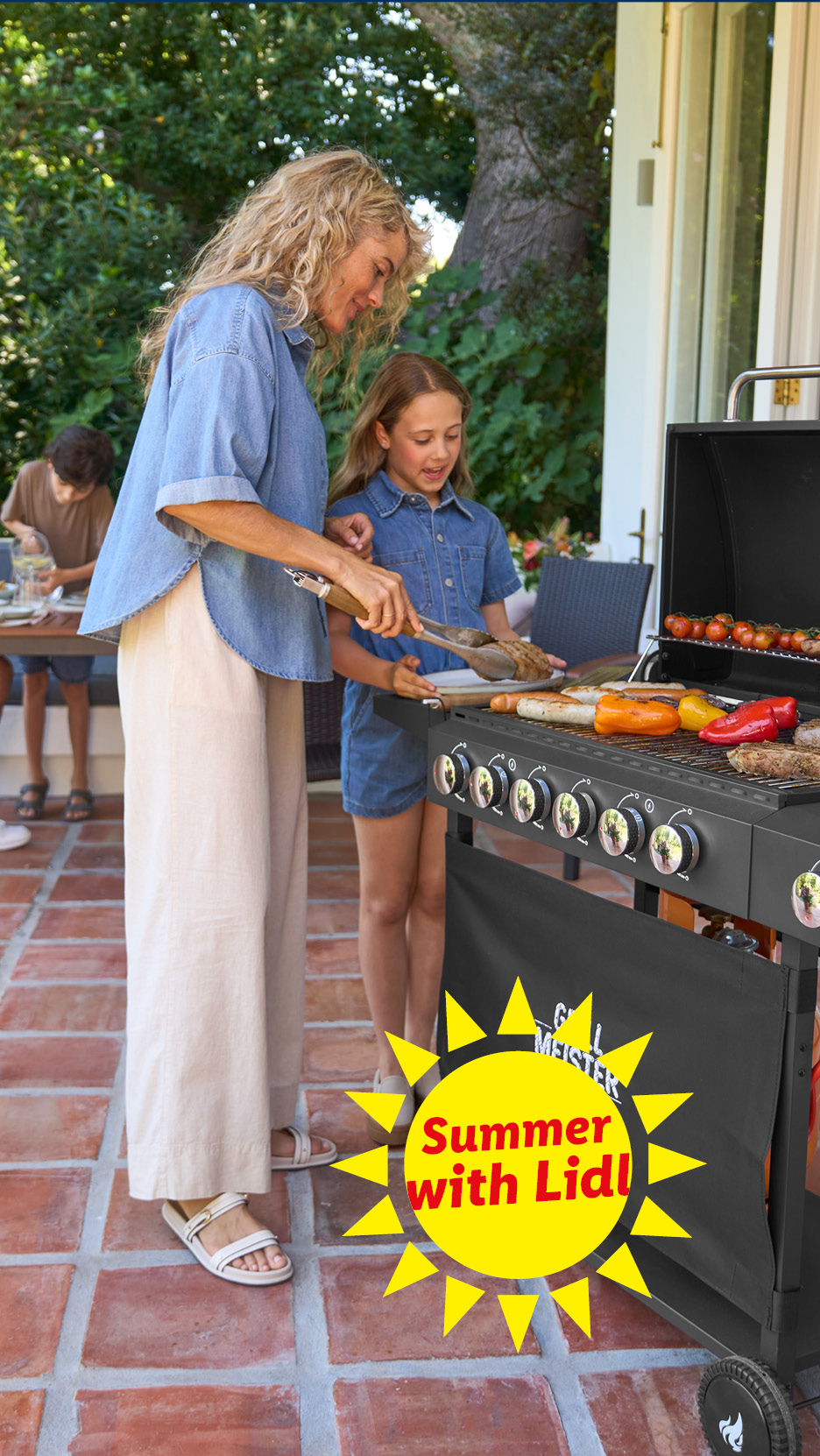 Family grilling outdoors with a gas barbecue, featuring grilled vegetables and meats. Summer with Lidl.