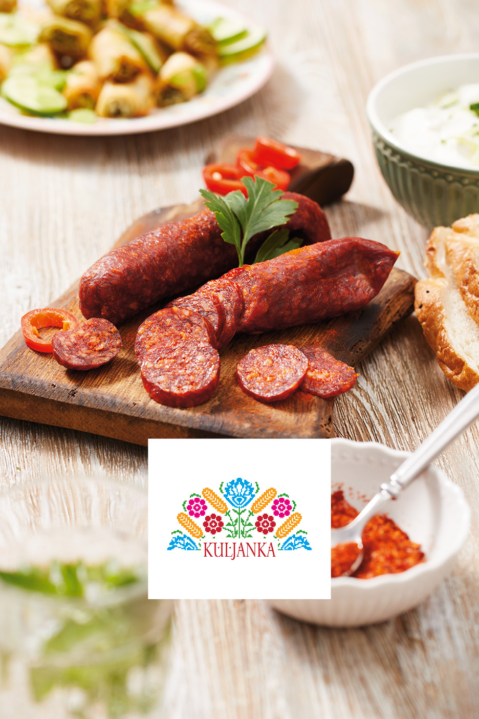 Spicy sausages, whole and sliced, on a wooden board with a folk art-inspired logo.