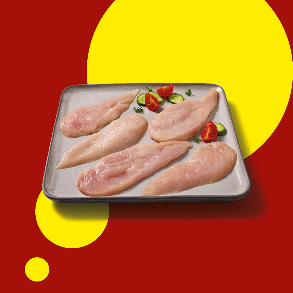 Raw chicken fillets on a tray with cucumber and tomato slices on a red and yellow background.