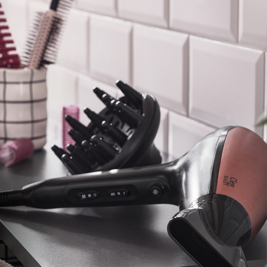 A black and rose gold hairdryer with a diffuser attachment on a counter.