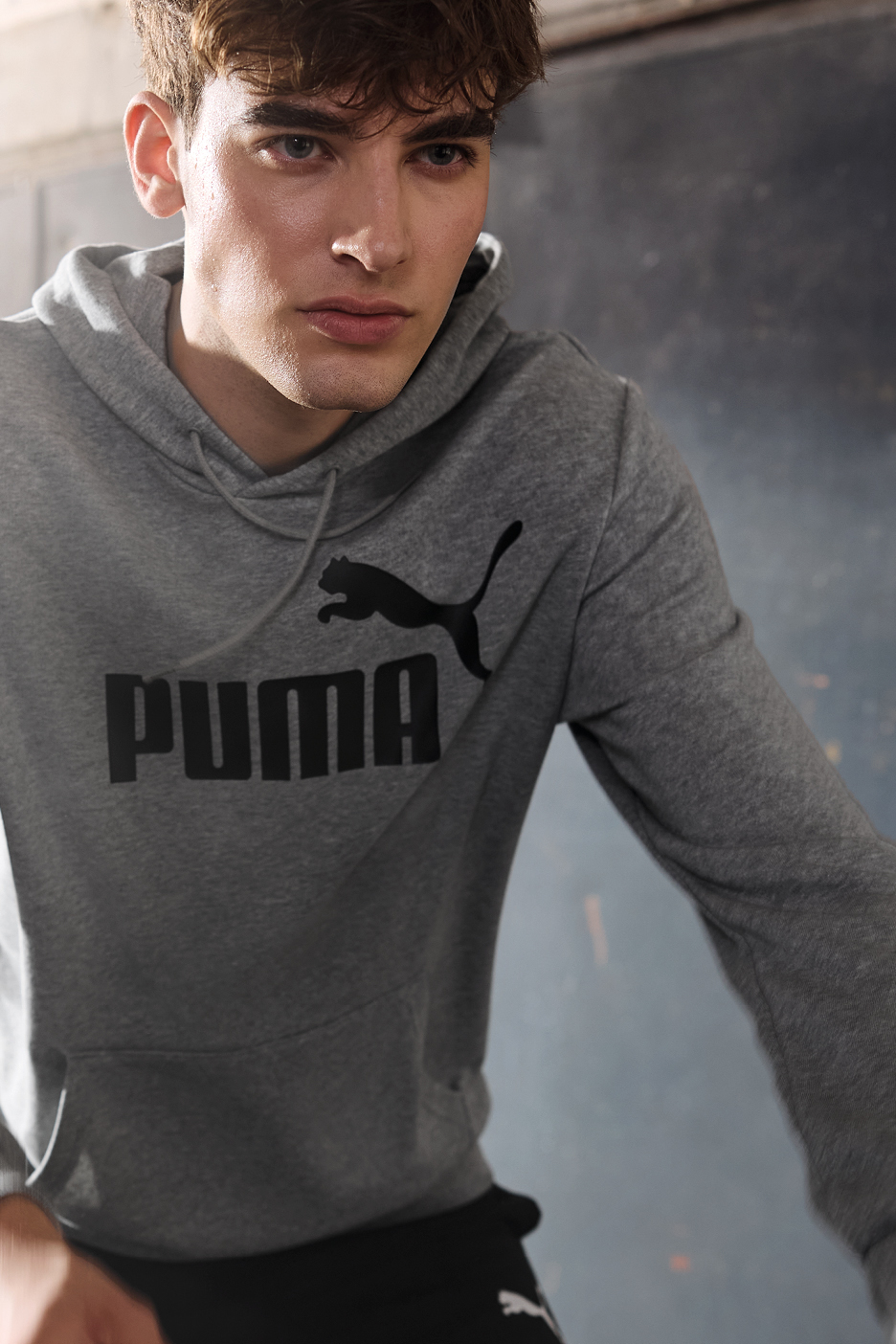 A man in a gray Puma hoodie with a black logo, looking directly at the camera.