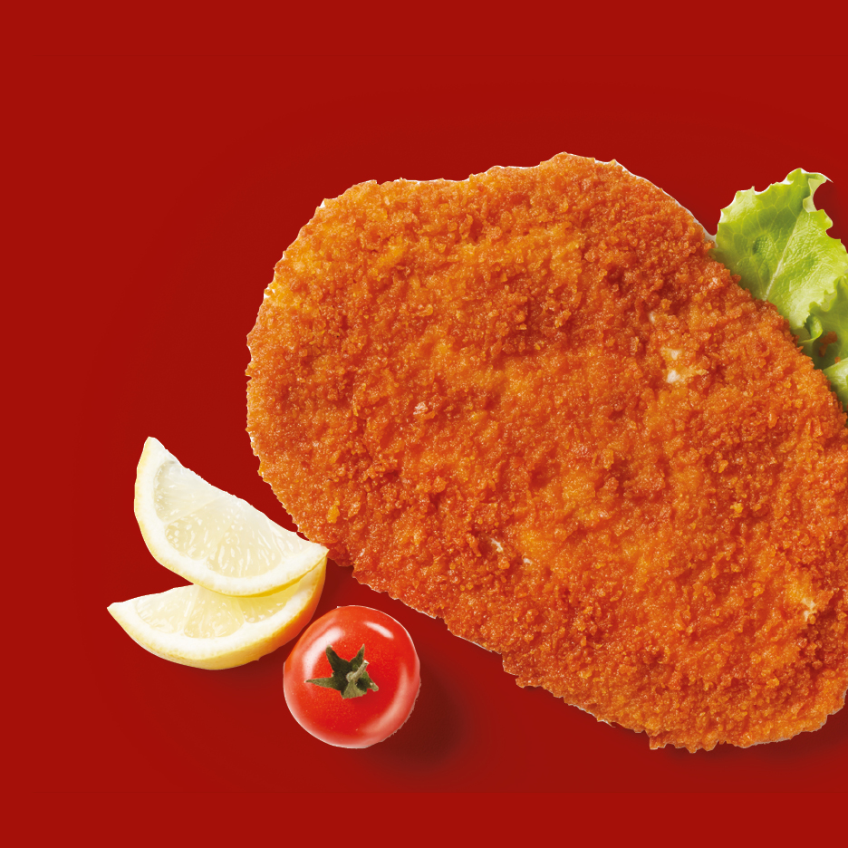 Crispy breaded schnitzel with lemon wedges, a cherry tomato, and lettuce on a red background.