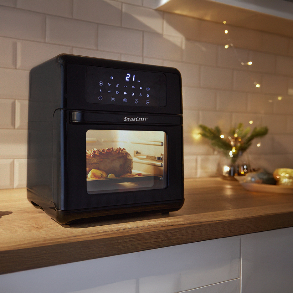 SilverCrest air fryer oven cooking a roast on a kitchen counter with festive lights.