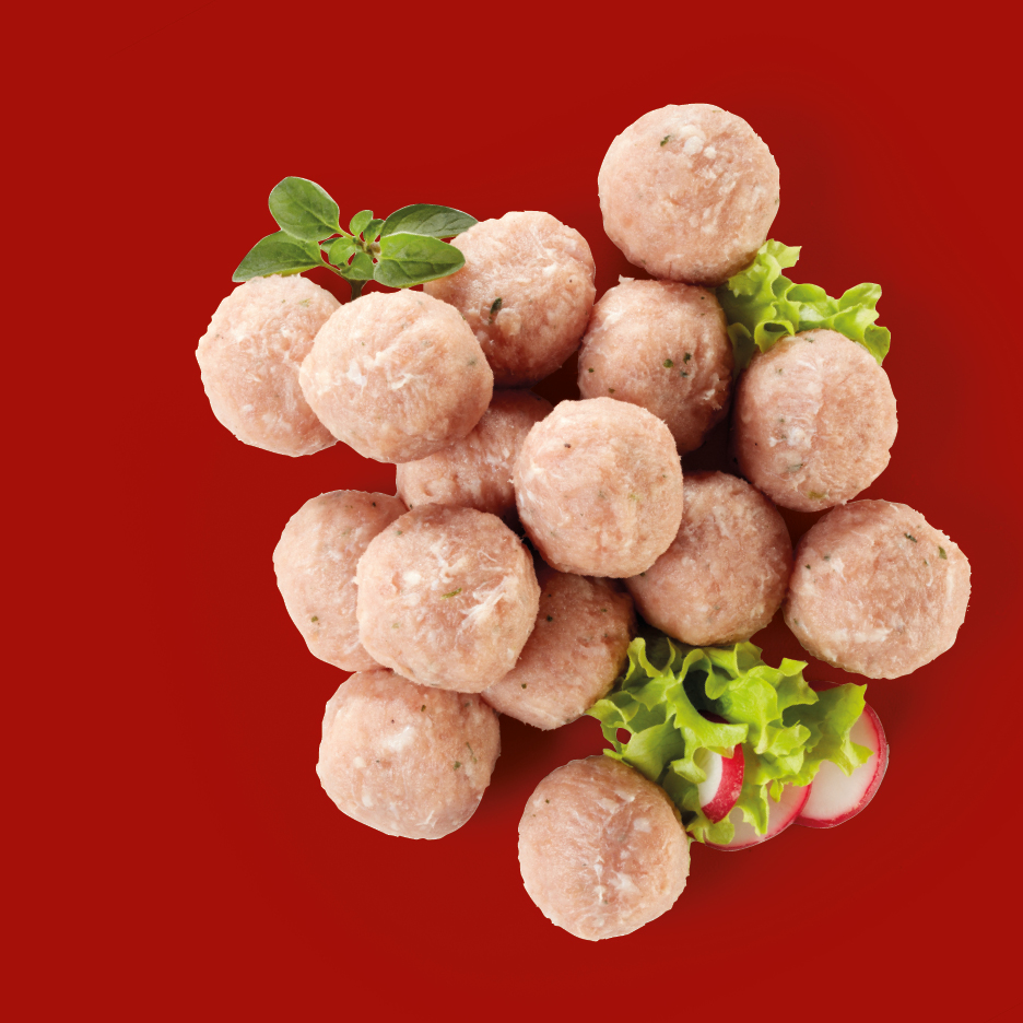 A pile of raw meatballs with lettuce, radish slices, and a sprig of oregano on a red background.