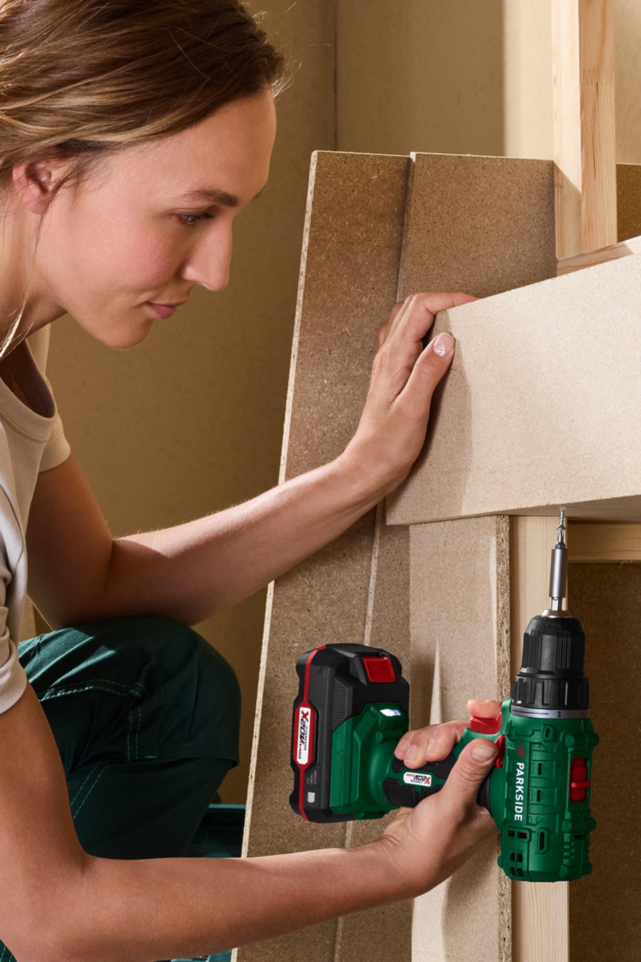 A woman uses a cordless drill to assemble wooden furniture.