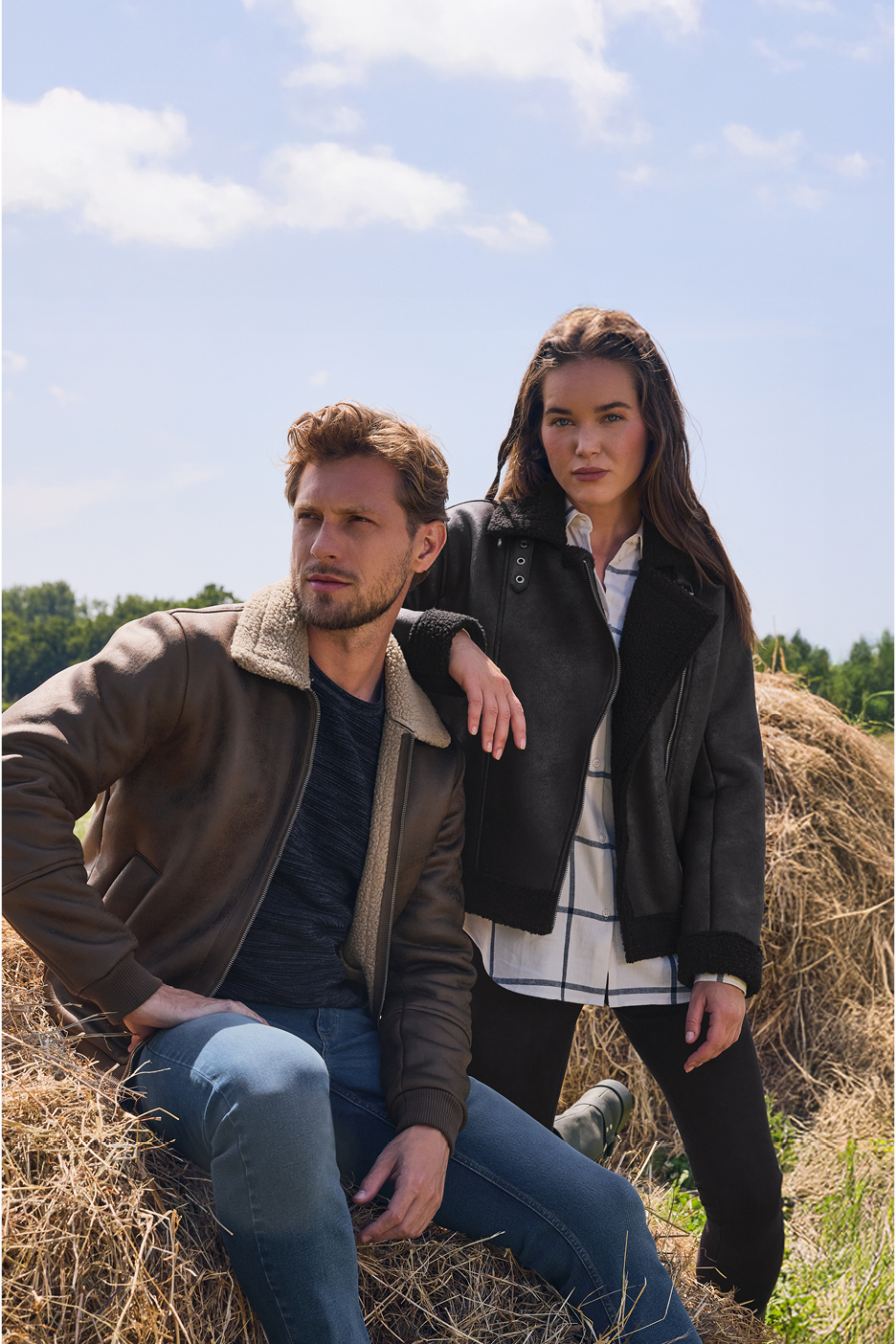 Man and woman in Biker jackets and jeans sitting on hay bales outdoors.