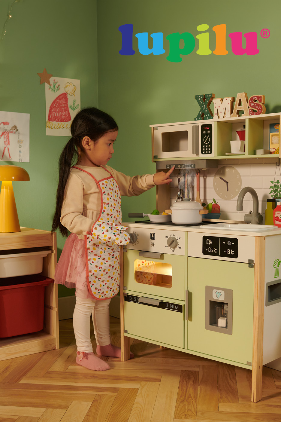 A child playing with a wooden toy kitchen set decorated for Christmas.
