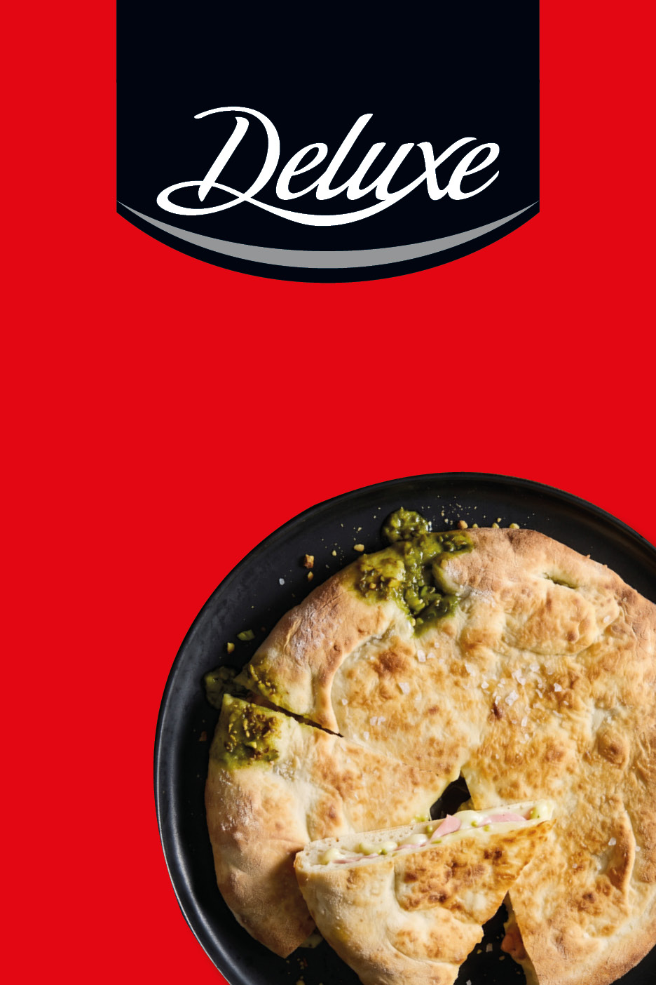 A deluxe stuffed flatbread with pistachio pesto and ham on a black plate against a red background.