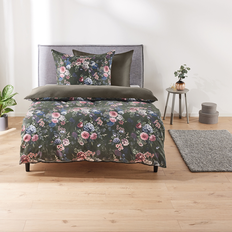 Floral duvet cover set on a bed with a grey headboard, side table, and rug.