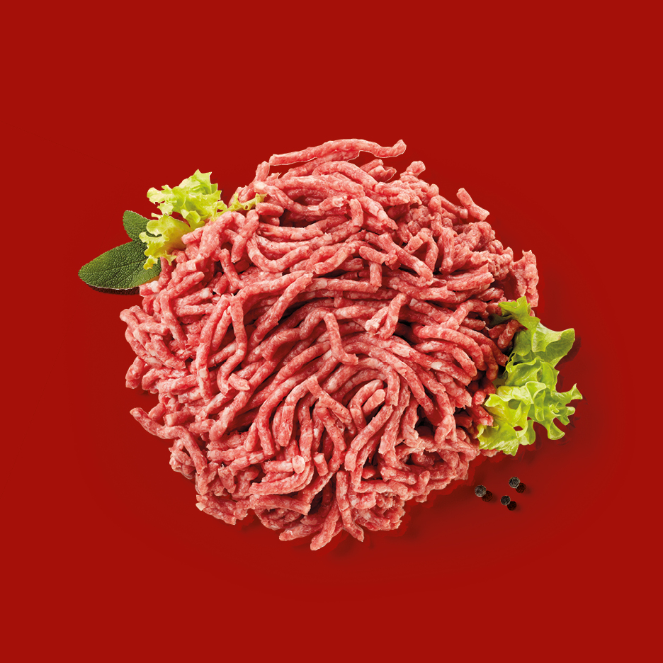 Fresh minced meat with lettuce, sage, and peppercorns on a red background.