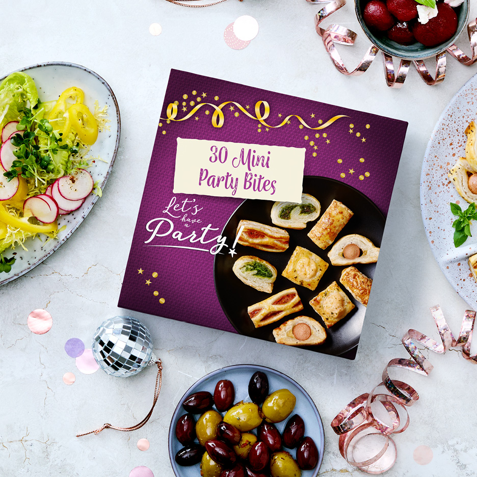 A box of '30 Mini Party Bites' surrounded by party food like salad, olives, and berries.