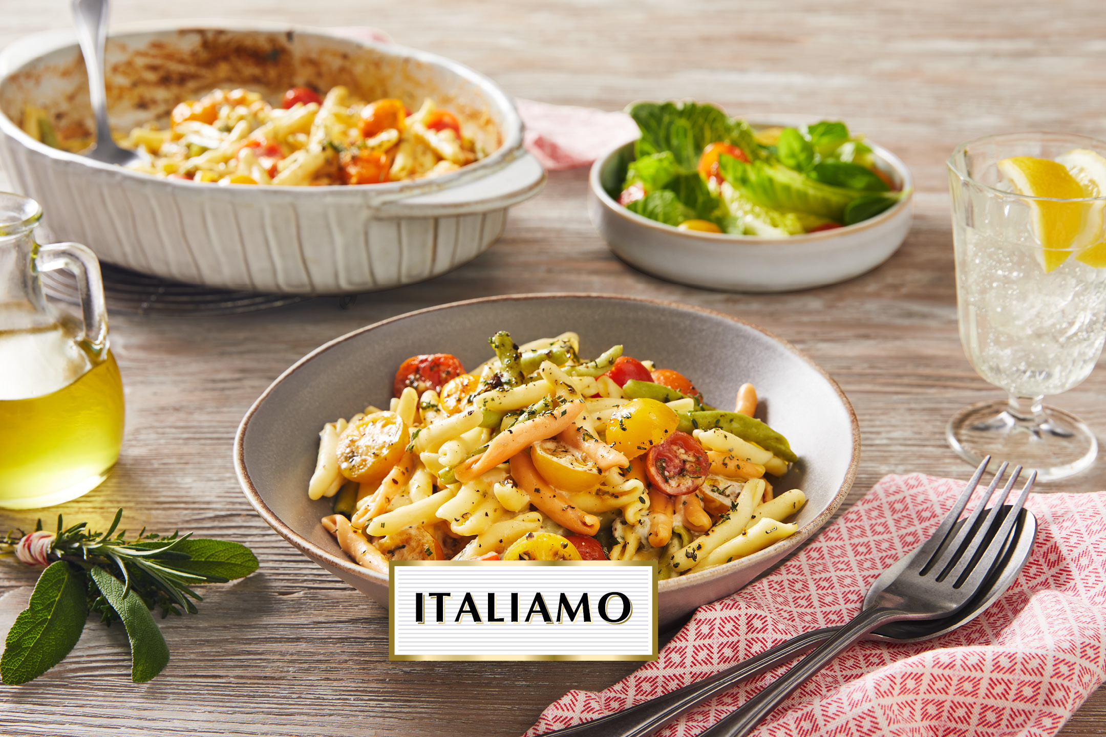 A bowl of colorful pasta with cherry tomatoes and herbs, with a text overlay 'ITALIAMO'.