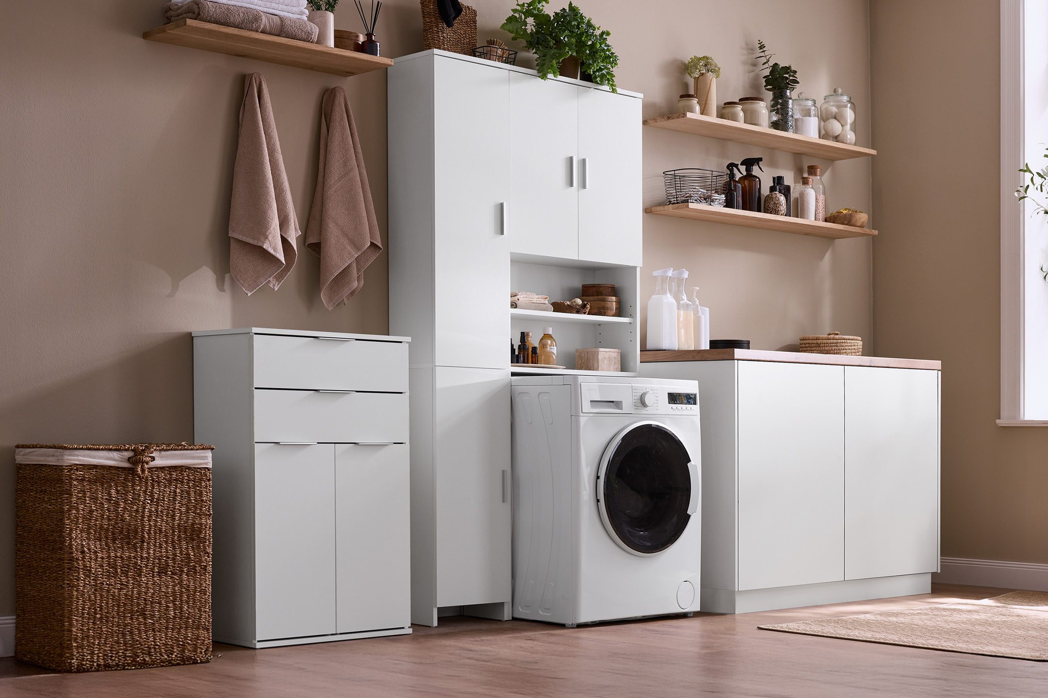 Laundry room with white cabinets, shelves, washing machine, and laundry basket.