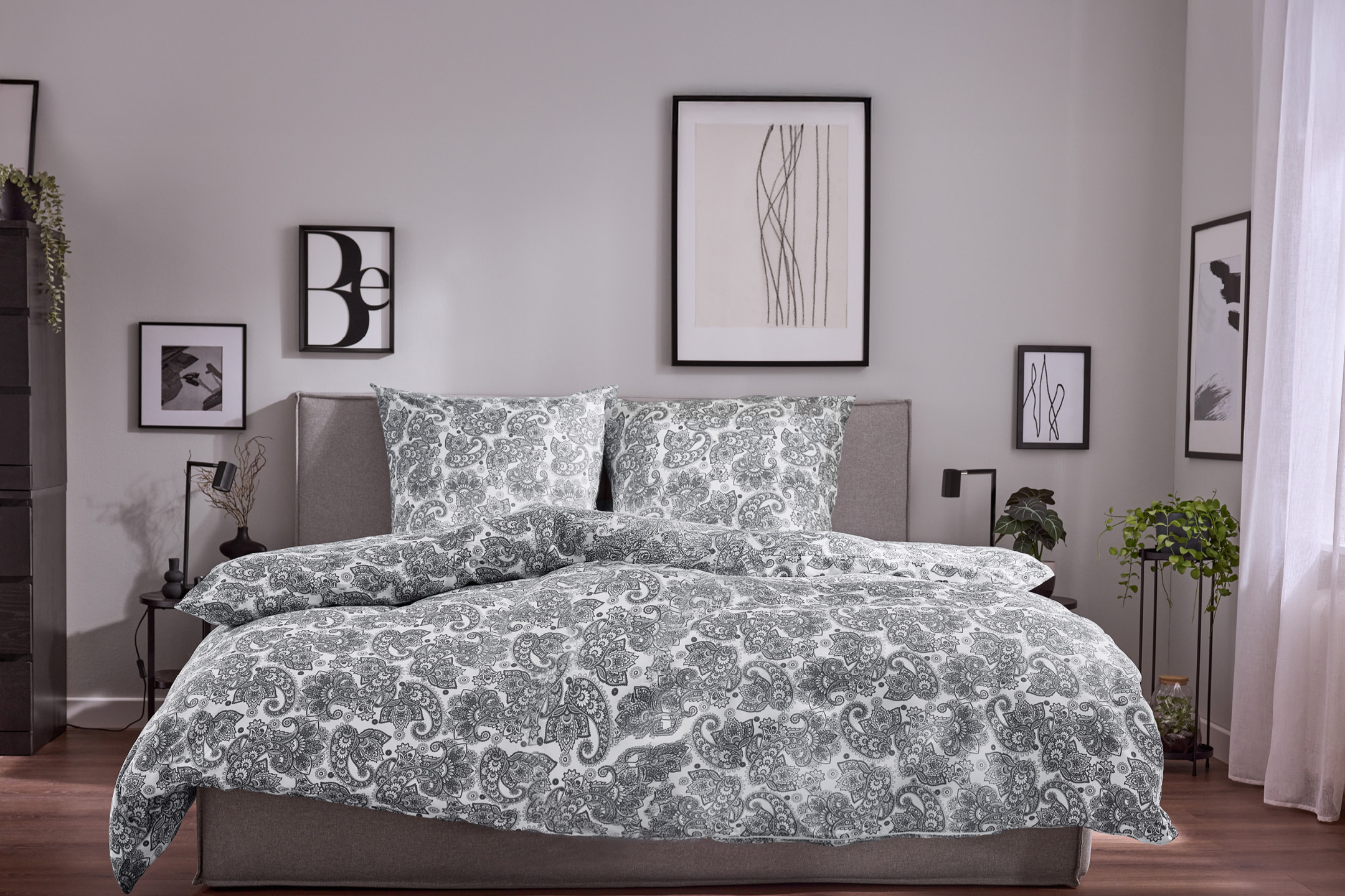 Bedroom with a bed featuring white and grey paisley patterned duvet cover and pillows.