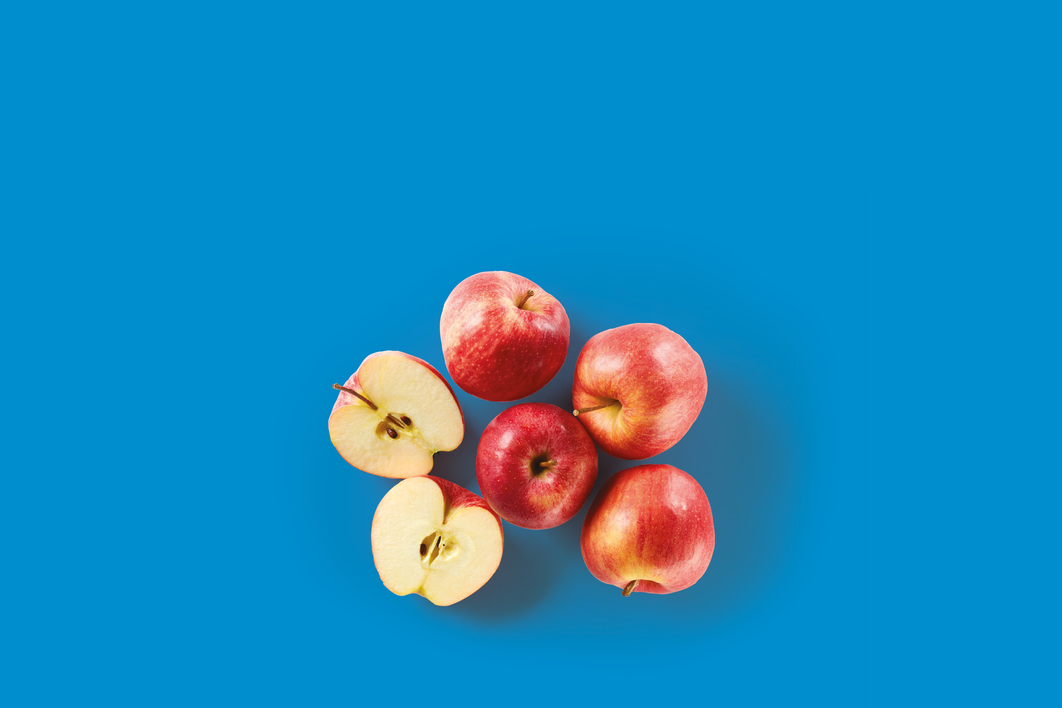 Red apples, some whole and some halved, on a blue background.