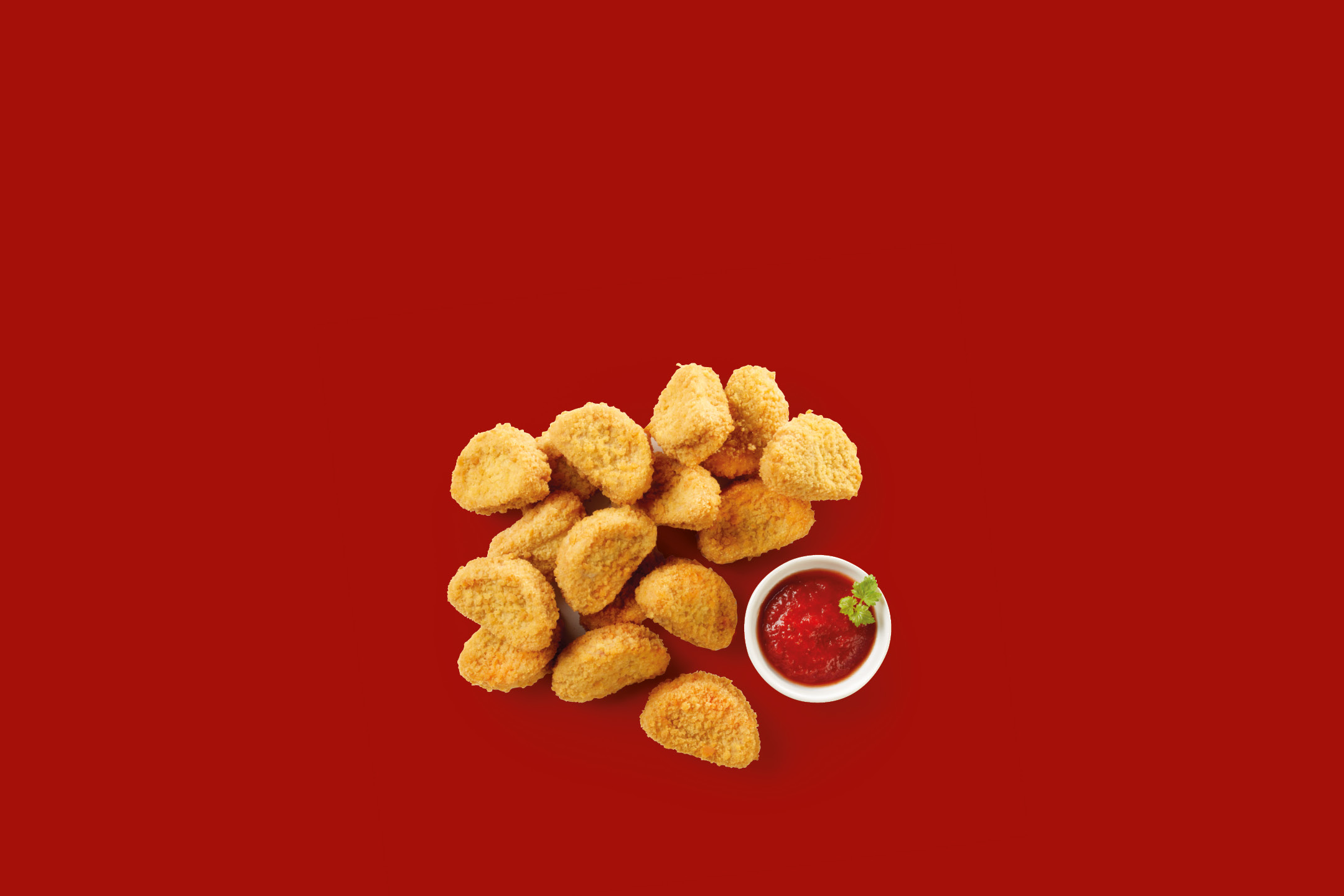 Crispy chicken nuggets with a bowl of ketchup on a red background
