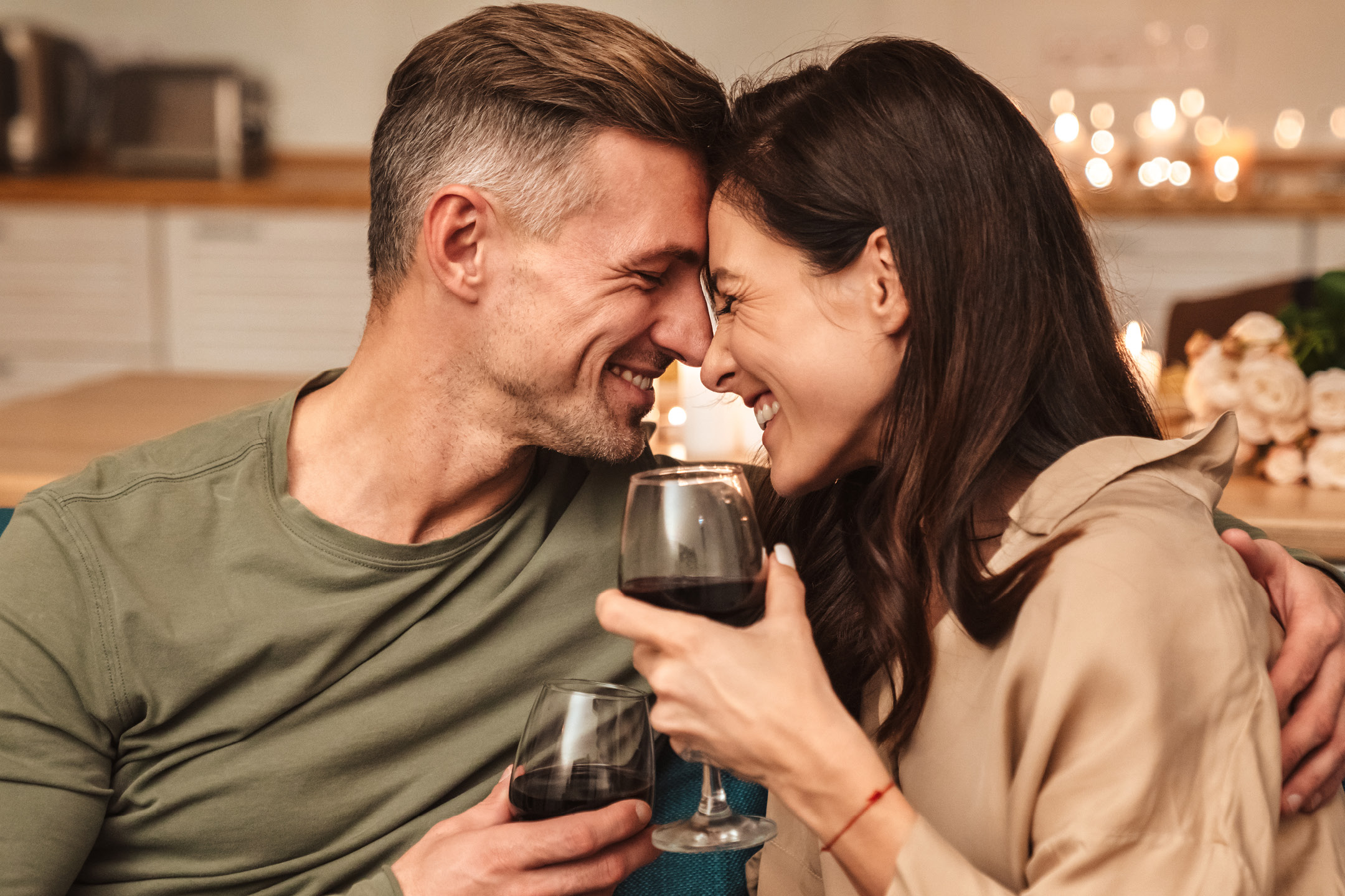 Happy couple enjoying red wine together, embracing and smiling.