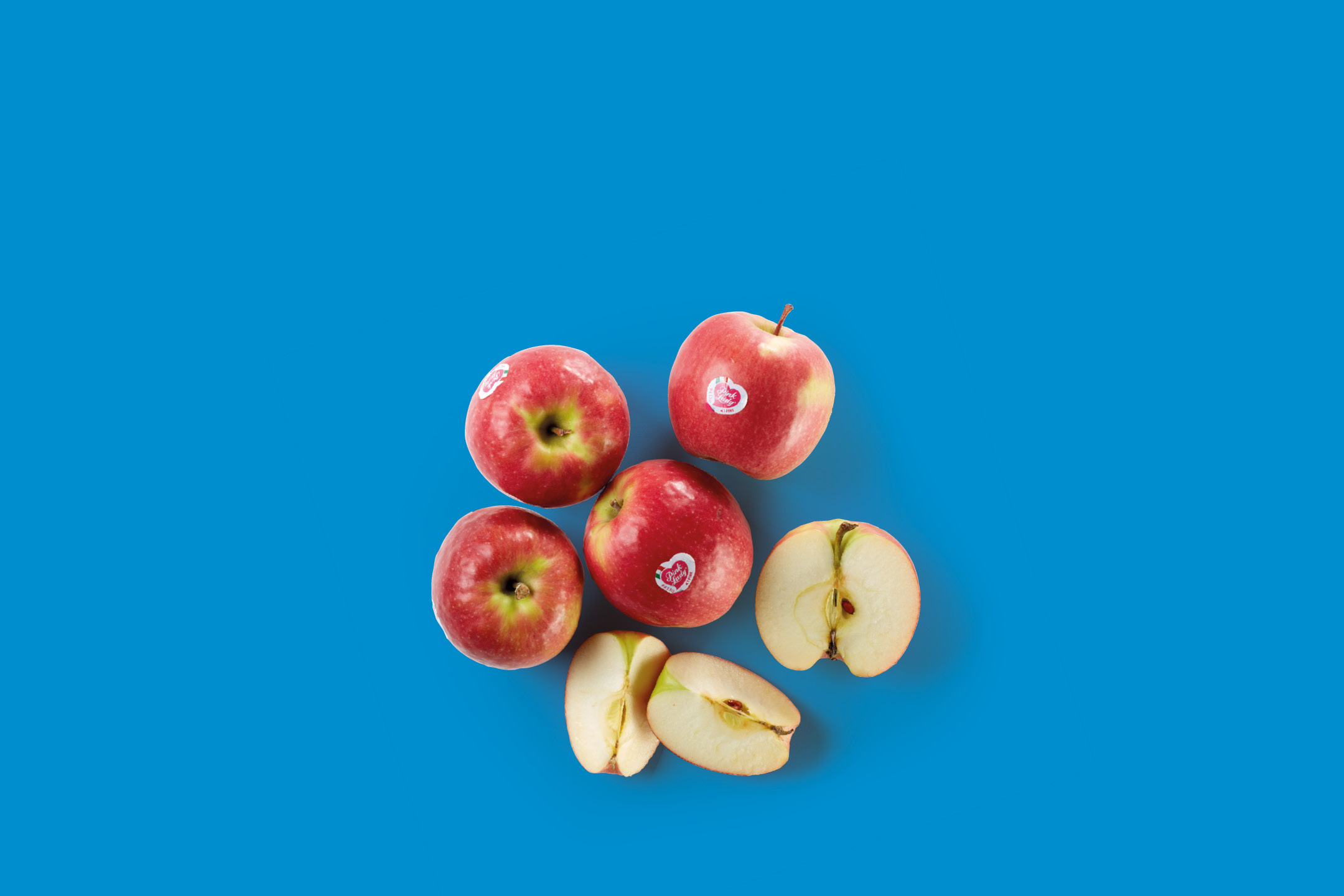 Red apples, some whole and some sliced, arranged on a blue background.
