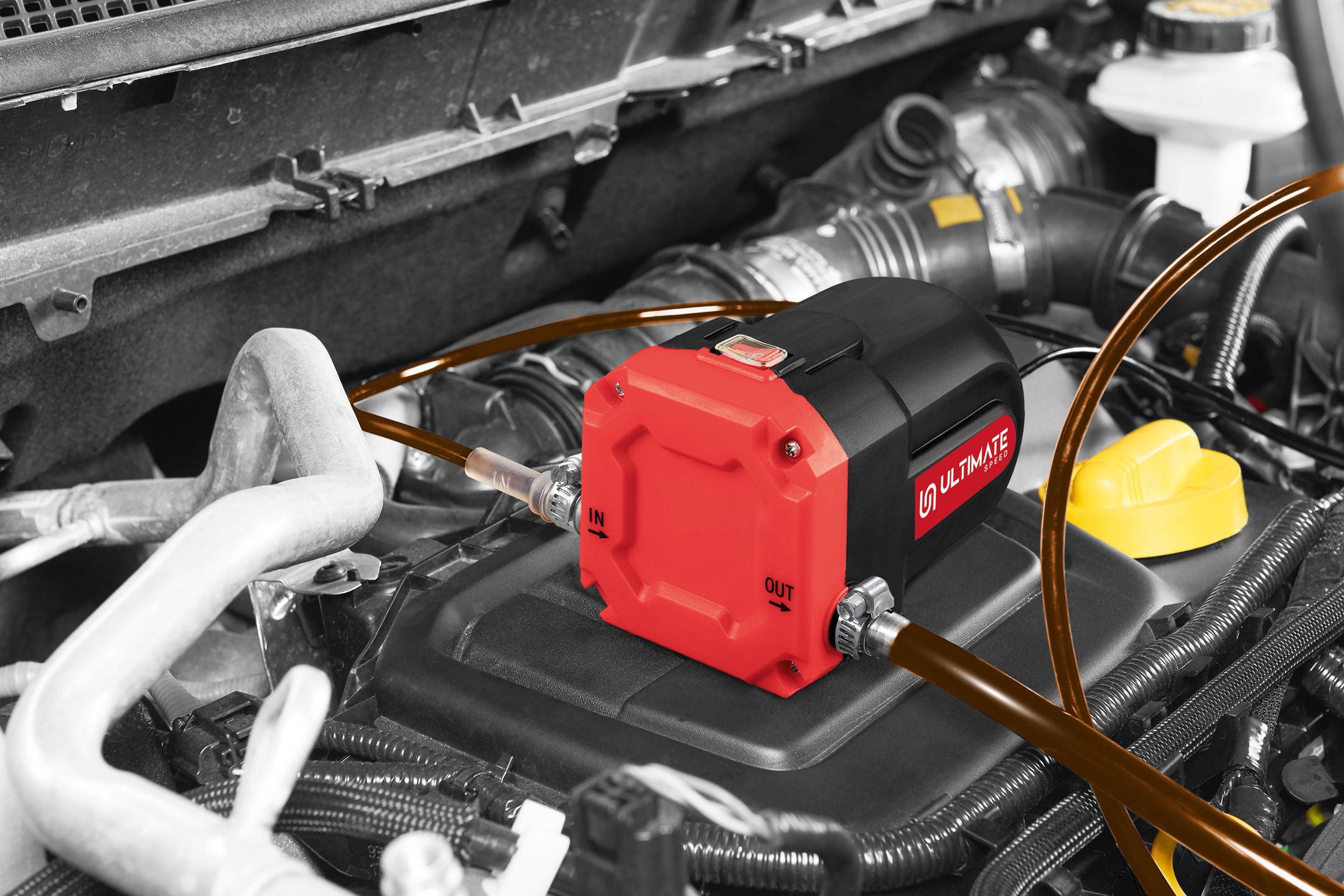 Oil extractor pump with hoses in a car engine bay, highlighting the red and black pump.