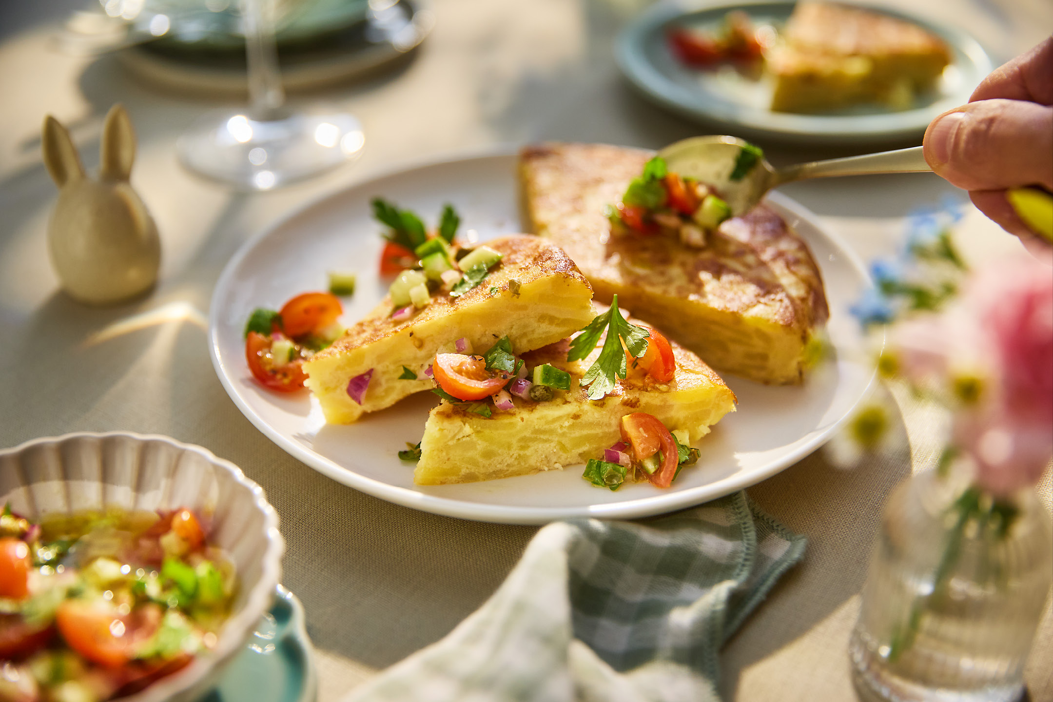 Spanish omelette slices with fresh salsa, served on a white plate with a small bunny decoration.