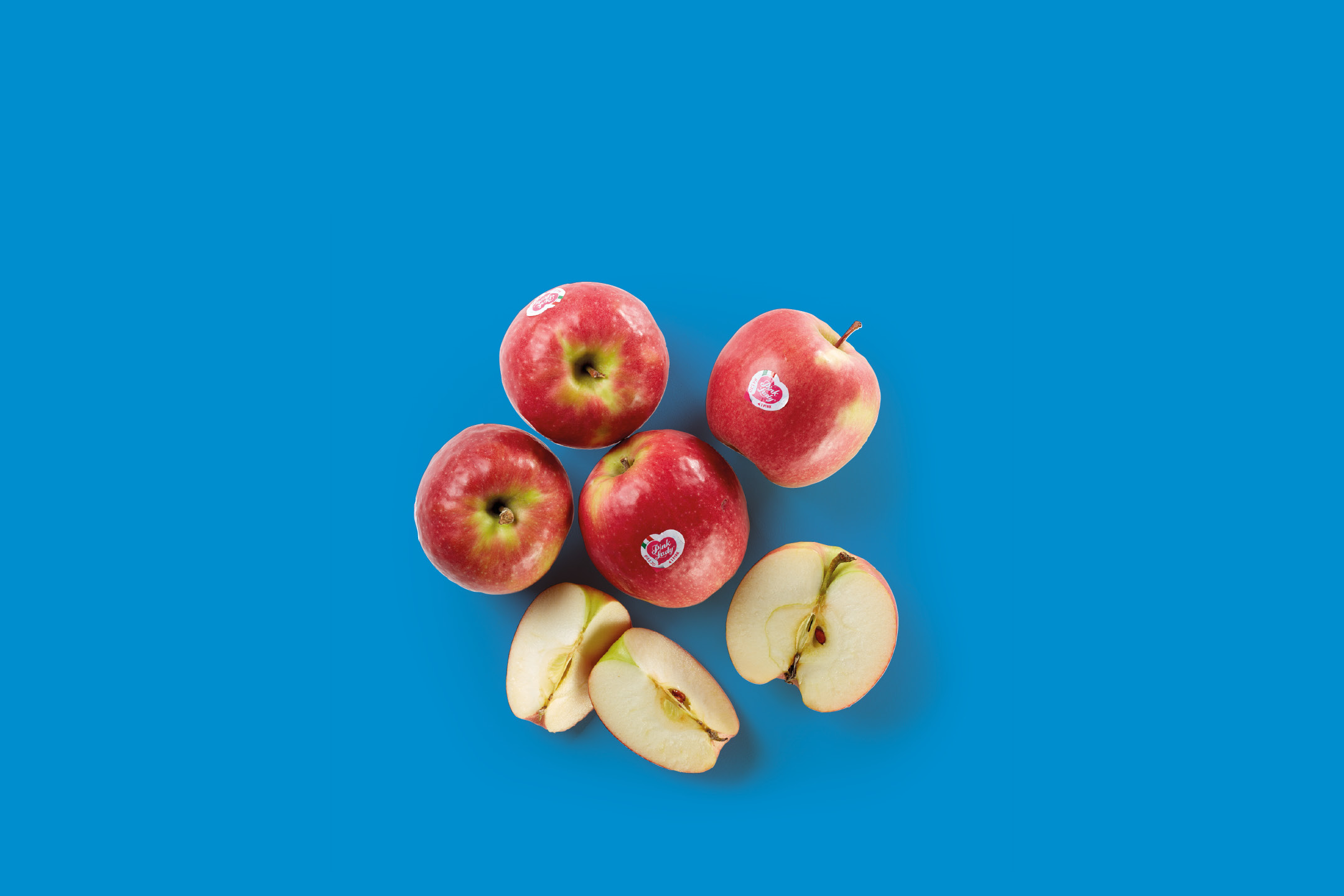 Red apples, some whole and some sliced, arranged on a blue background.