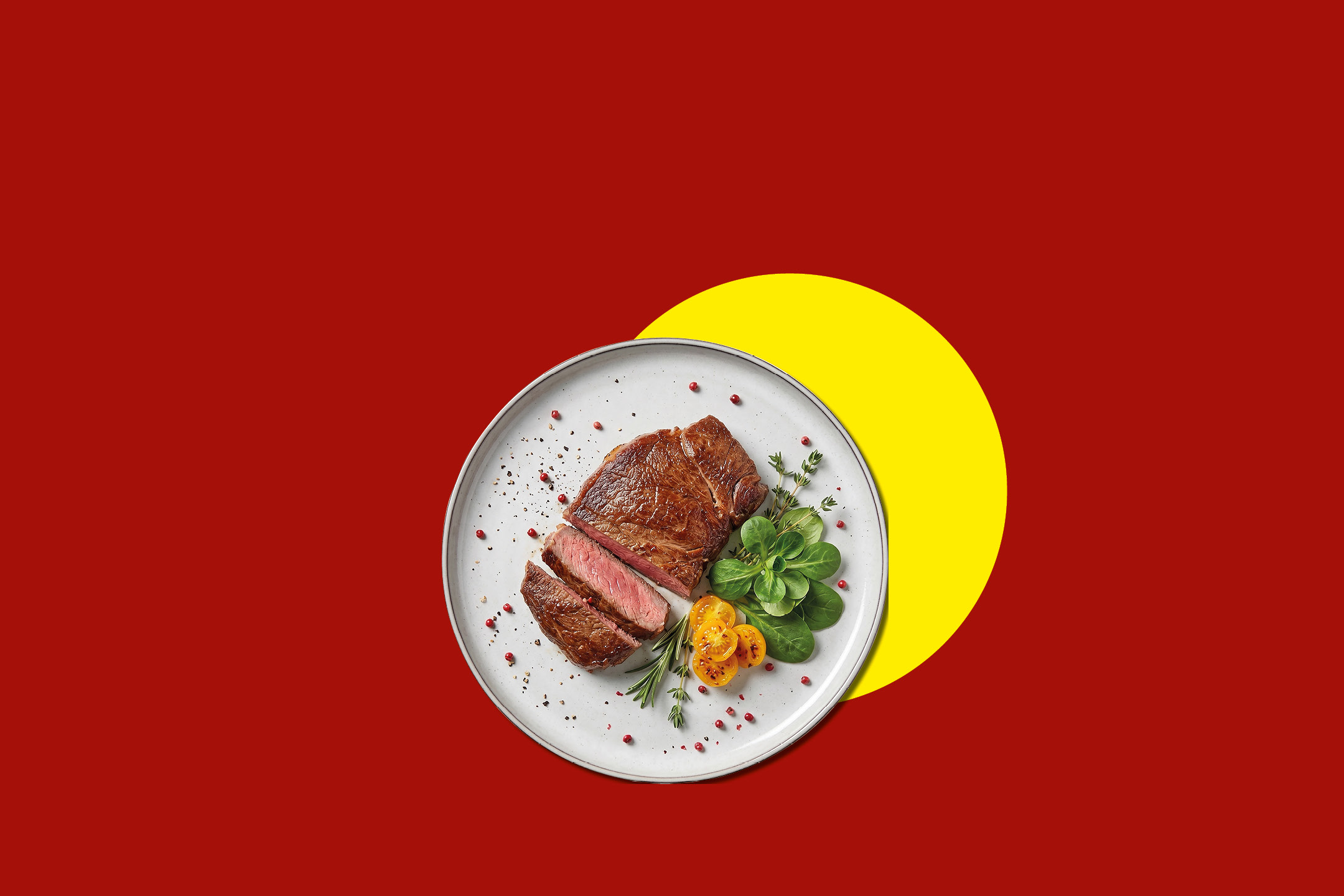 Grilled steak with herbs and cherry tomatoes on a plate, on a red and yellow background.