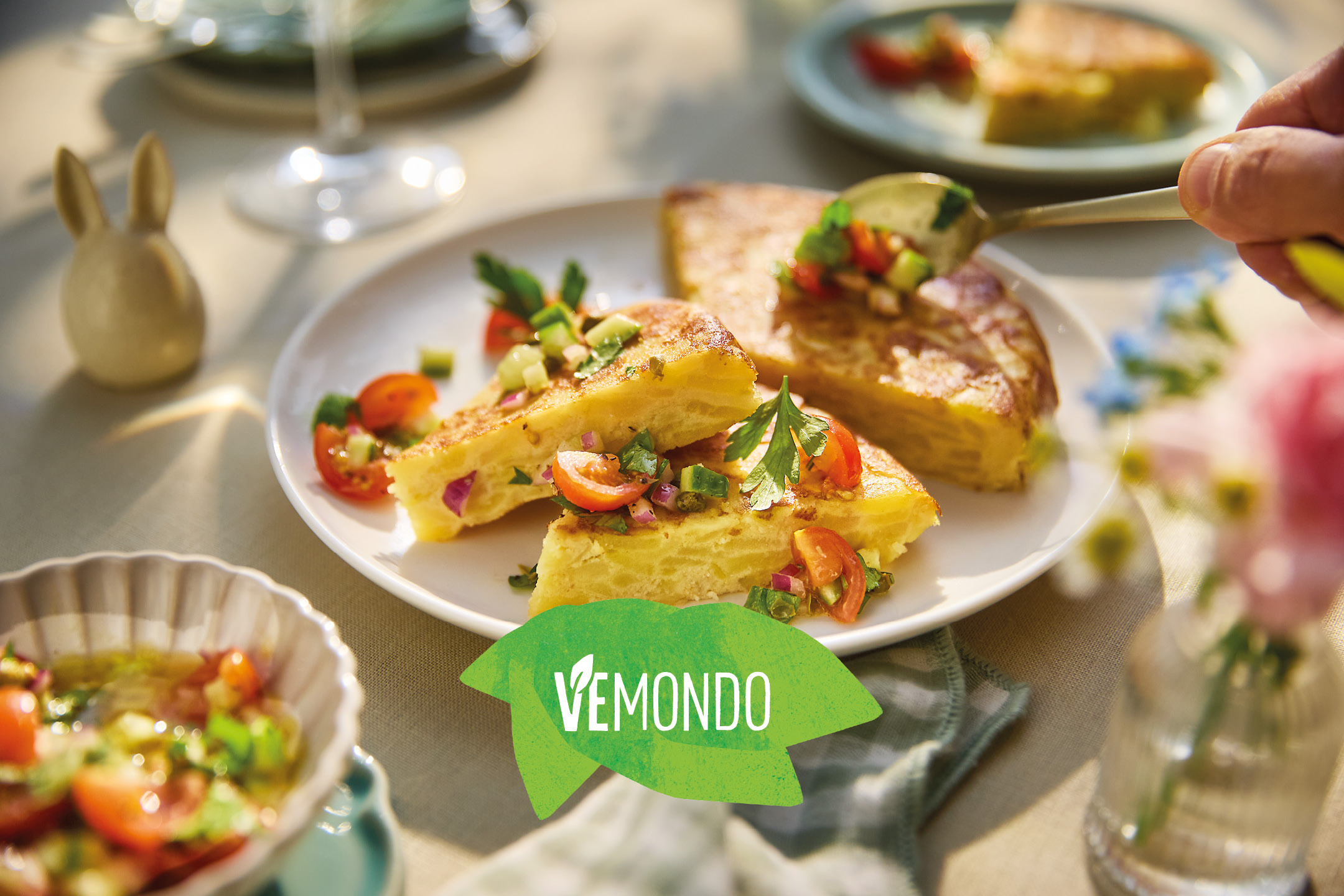 Slices of Spanish omelette with fresh salsa on a plate, with a hand serving more salsa.