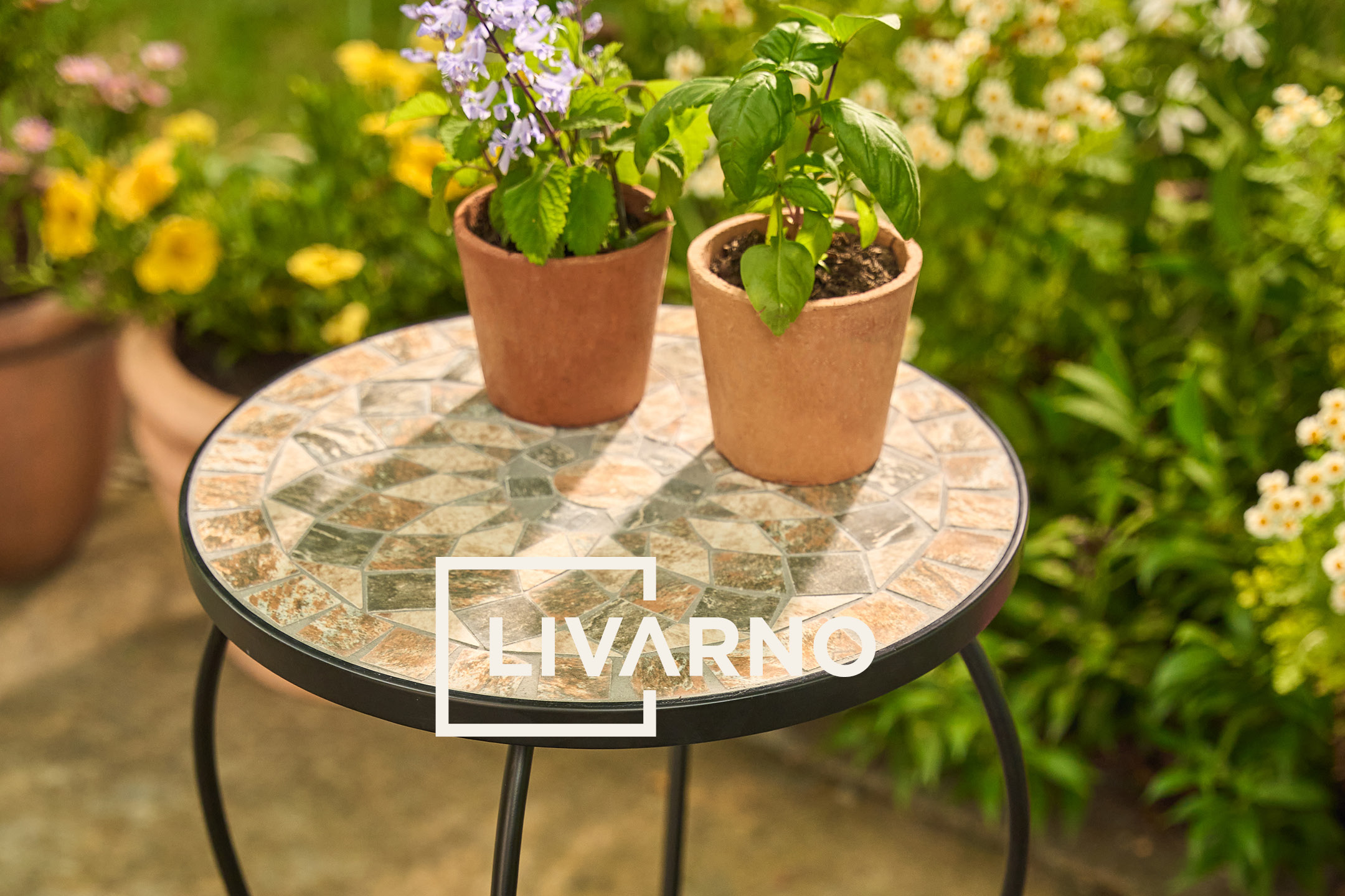 Two potted plants on a mosaic garden side table, with a blurred garden background.