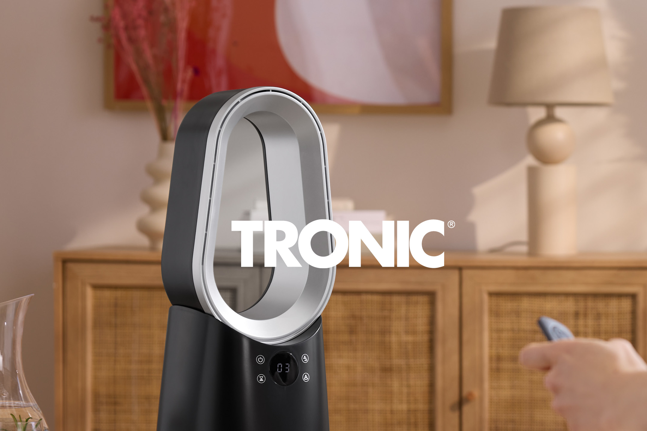 Black and silver bladeless fan with a digital display, in a living room setting.