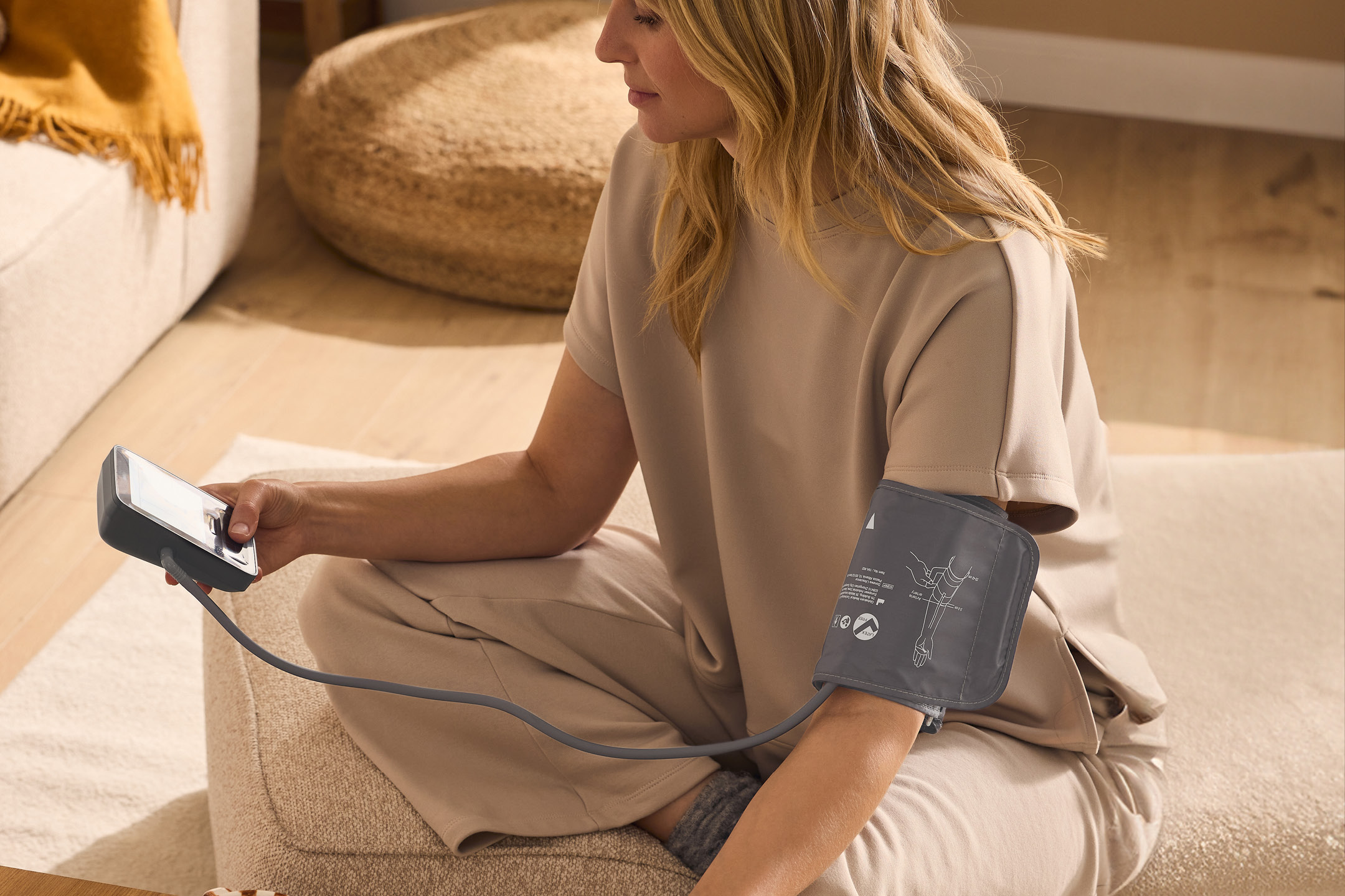 Woman measuring blood pressure at home with a blood pressure monitor.