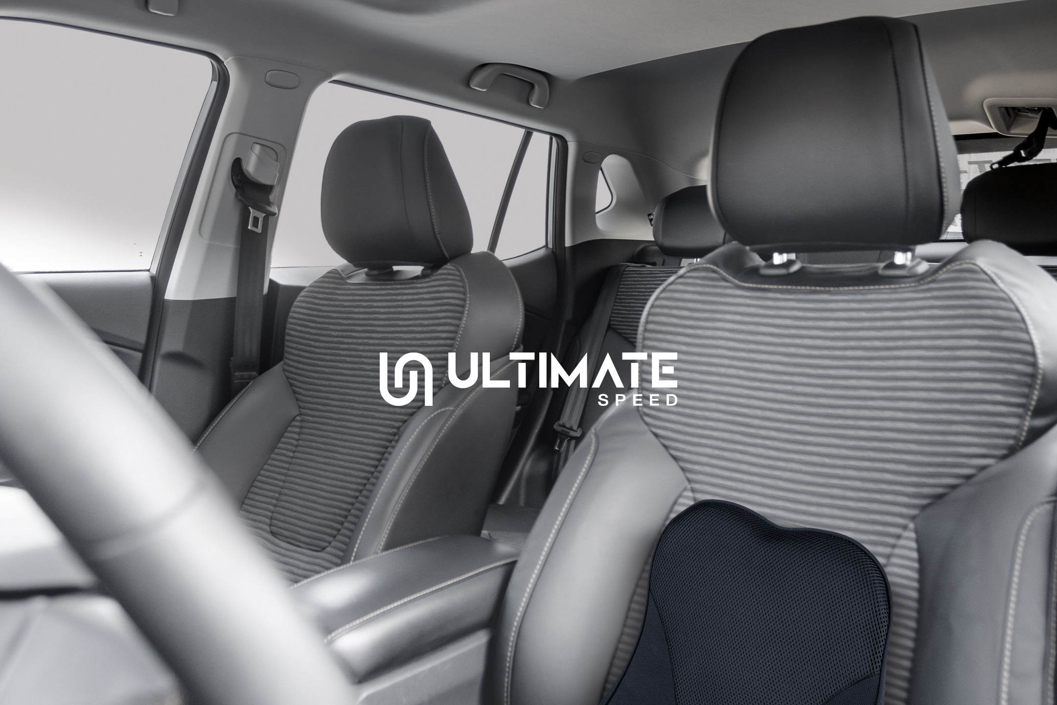 Car interior with a lumbar support cushion on the front passenger seat, featuring a logo.