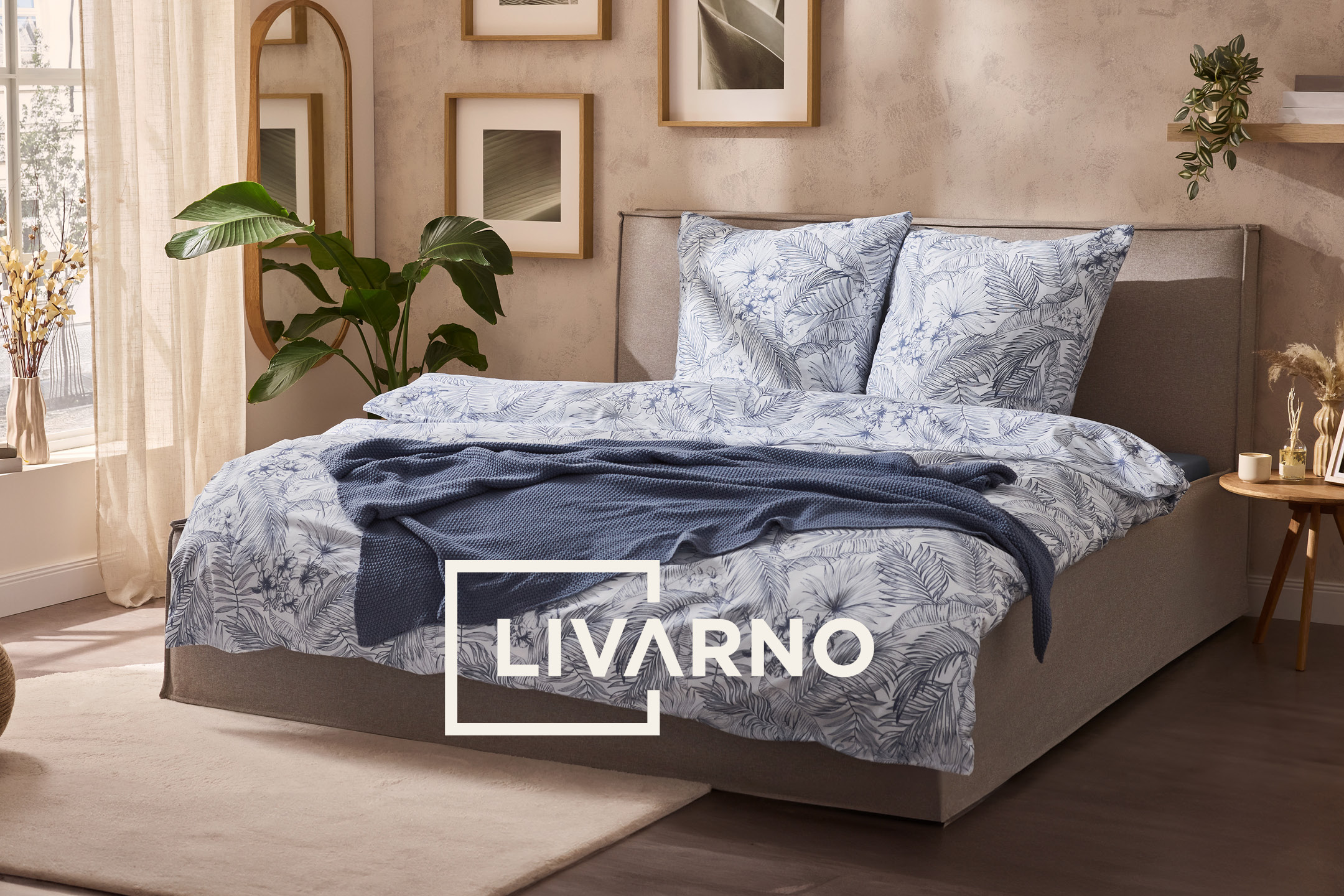 Bedroom with bed featuring blue and white botanical duvet cover, a blue throw, and framed art.