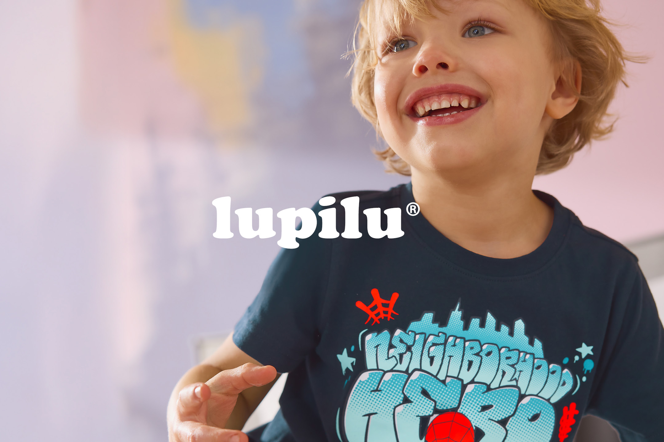 Smiling child wearing a dark blue t-shirt with a colorful graphic design.