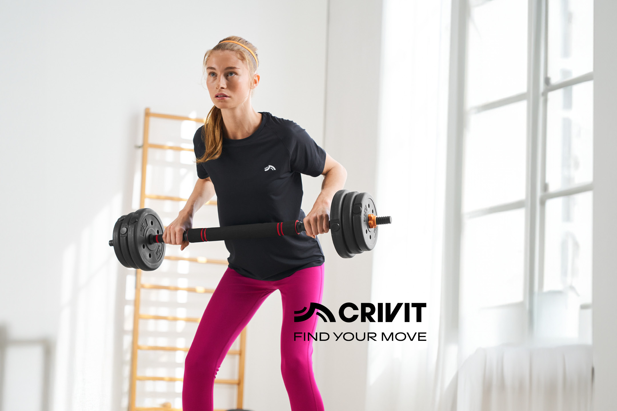 Woman in black t-shirt and pink leggings exercising with a barbell.