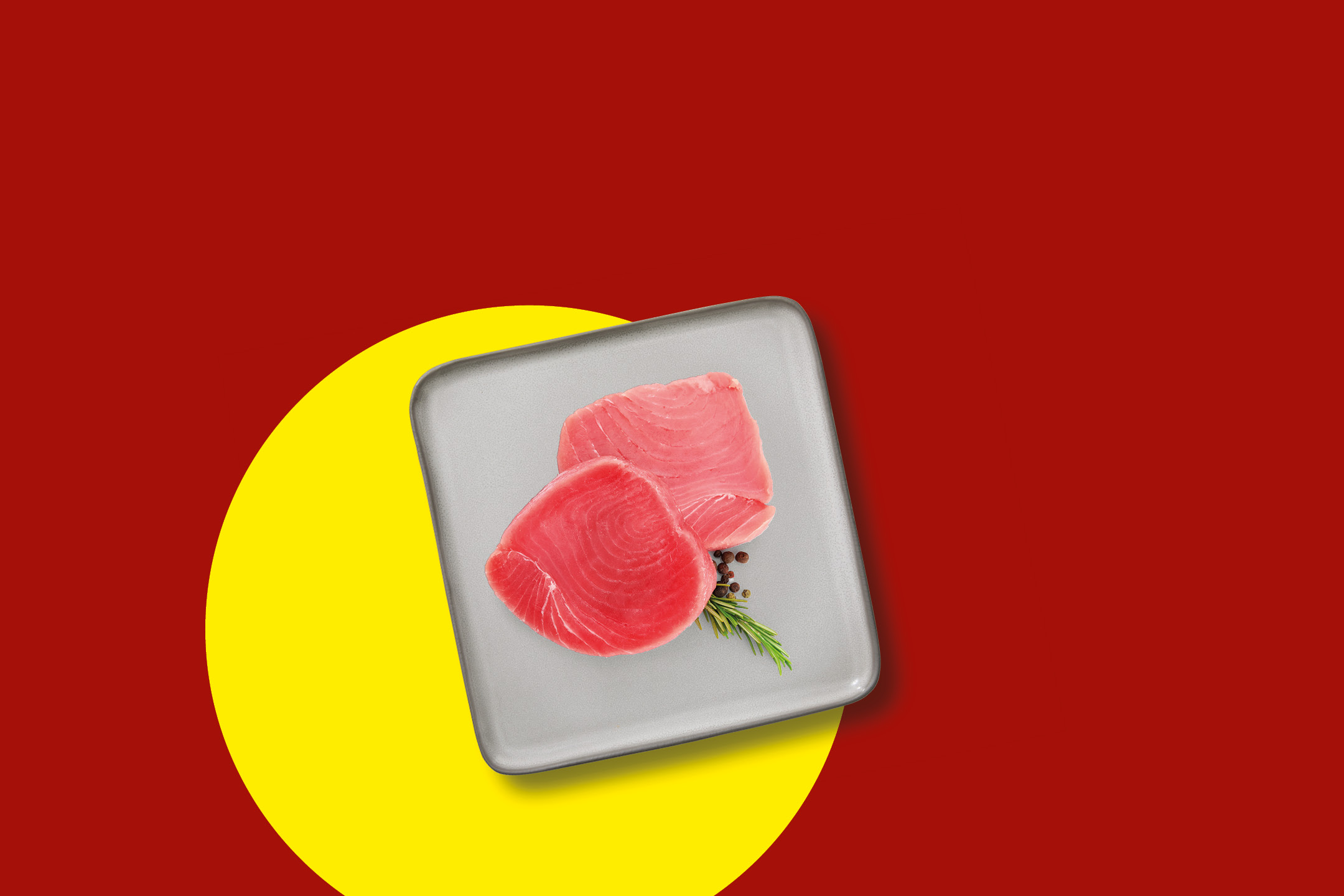 Two fresh tuna steaks with rosemary and peppercorns on a grey tray, on a red and yellow background.