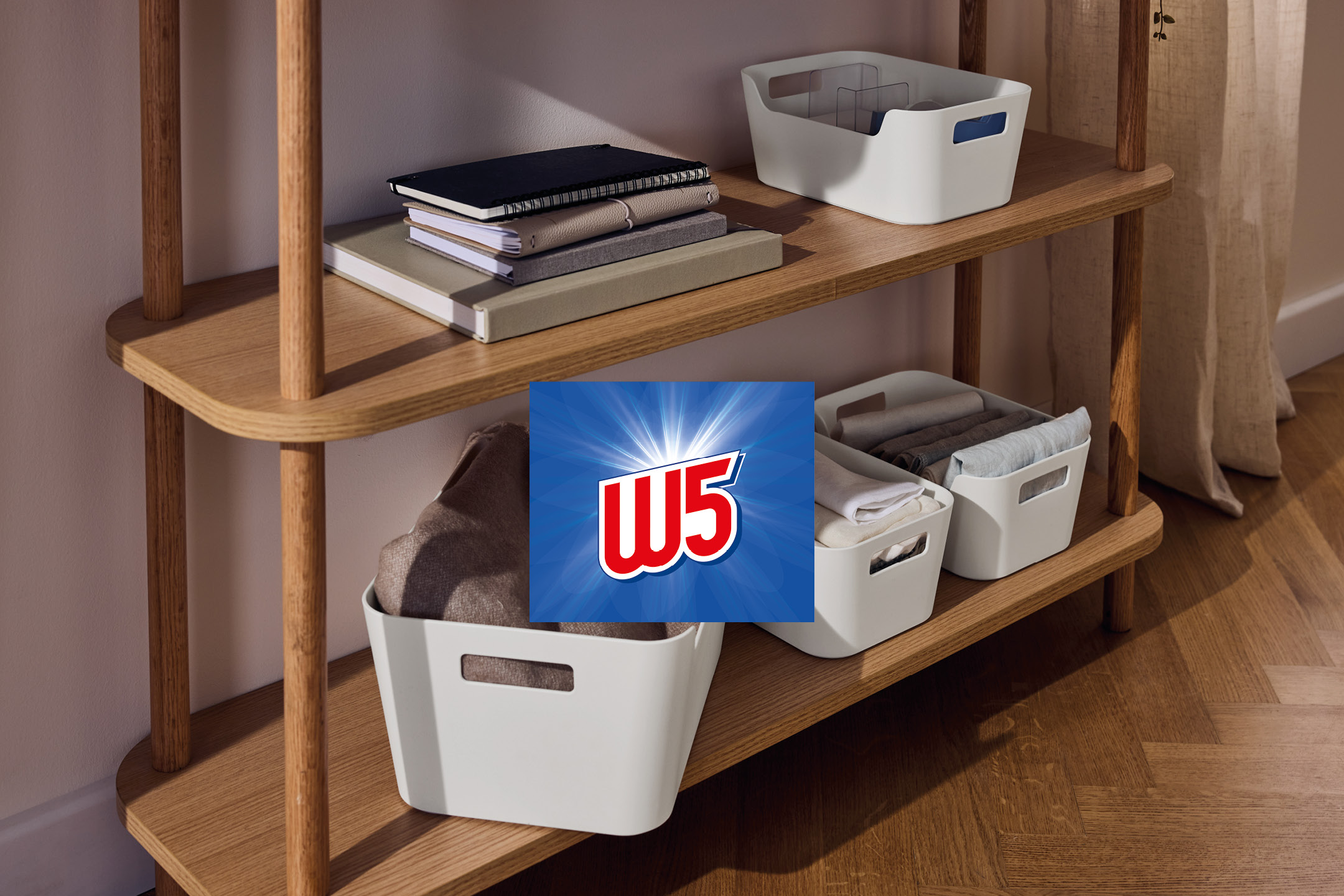 Wooden shelving unit with books and storage boxes containing textiles, W5 logo in top right.