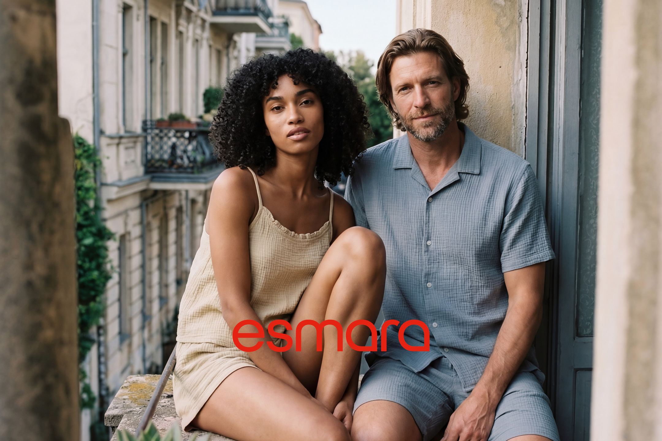 Man and woman in casual summer clothing, with a city balcony in the background.