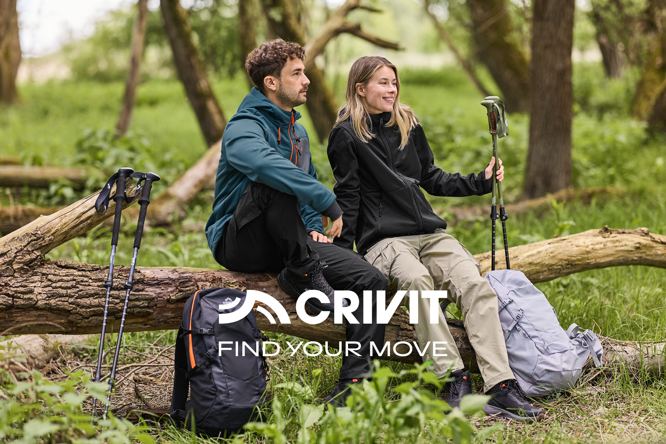 Two people in outdoor jackets with hiking poles, sitting on a log in a forest. Text: FIND YOUR MOVE.