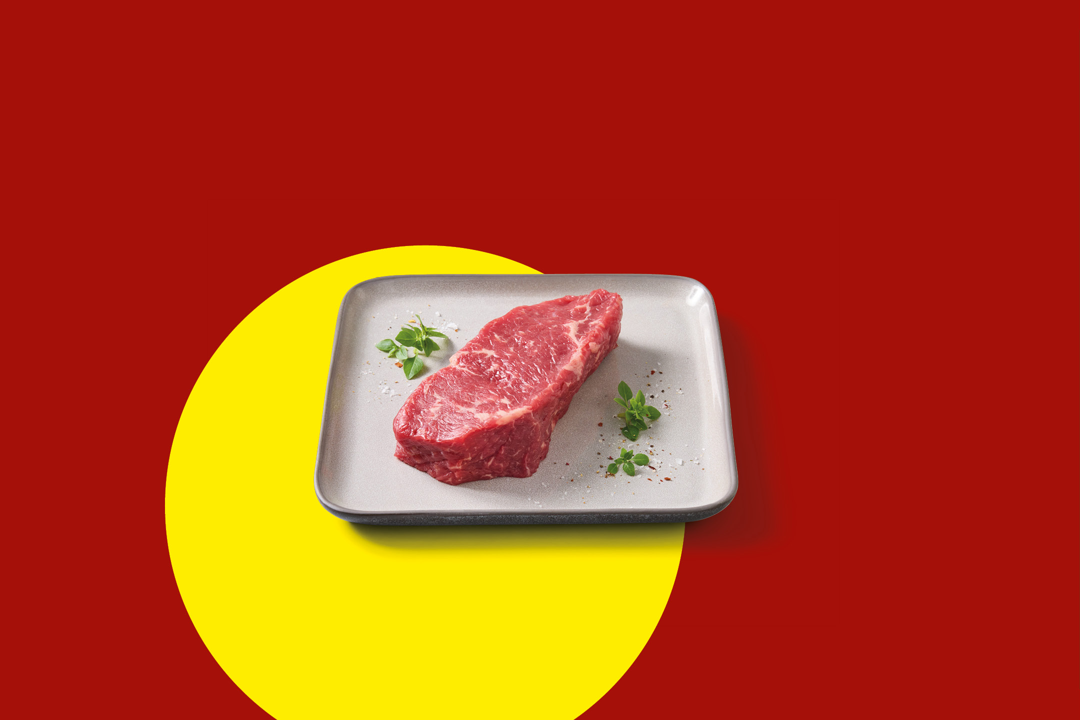 Raw beef steak on a plate with herbs, set against a red and yellow background.