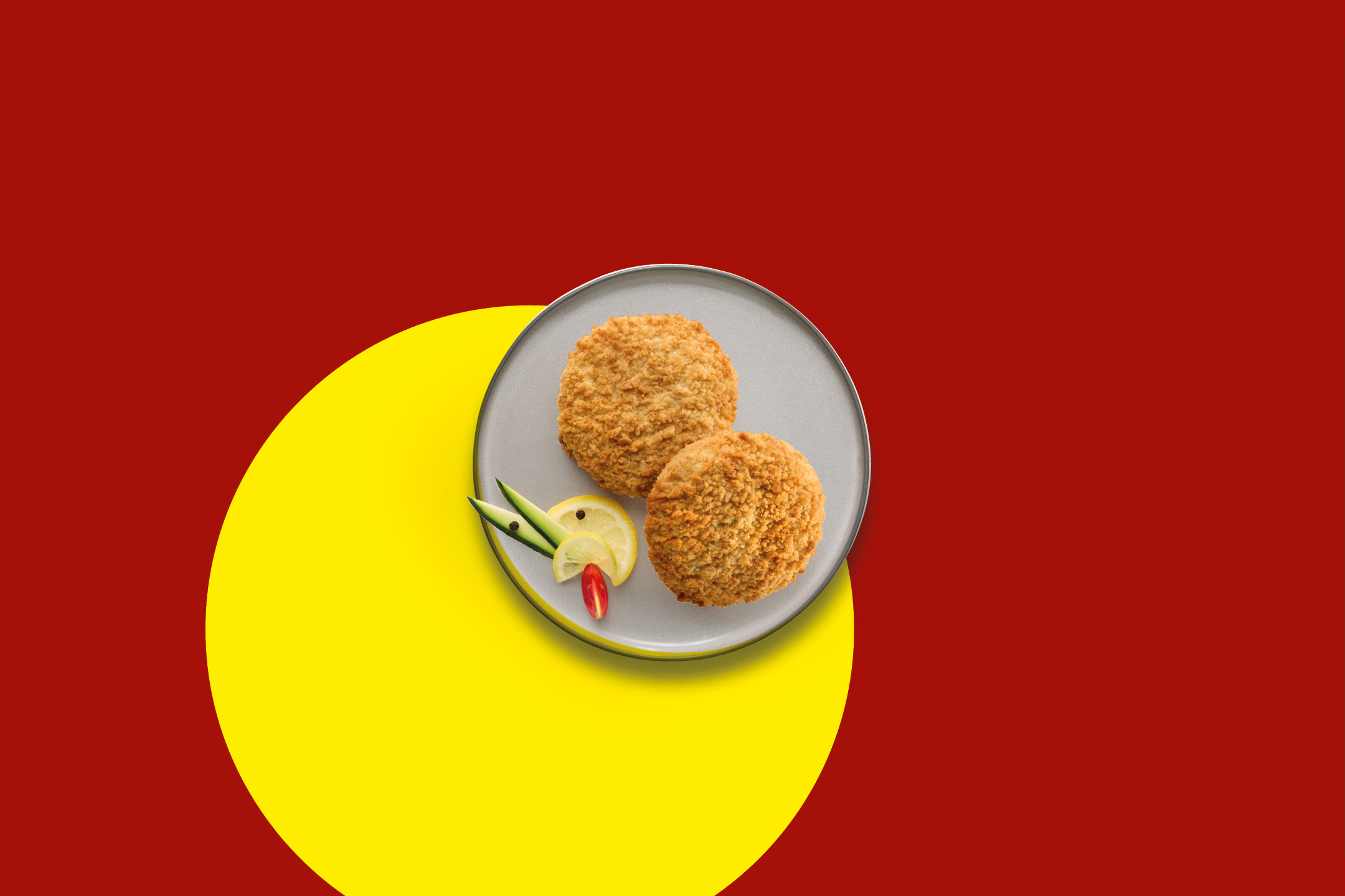 Two golden-brown breaded fish cakes on a plate with lemon and cucumber garnish.