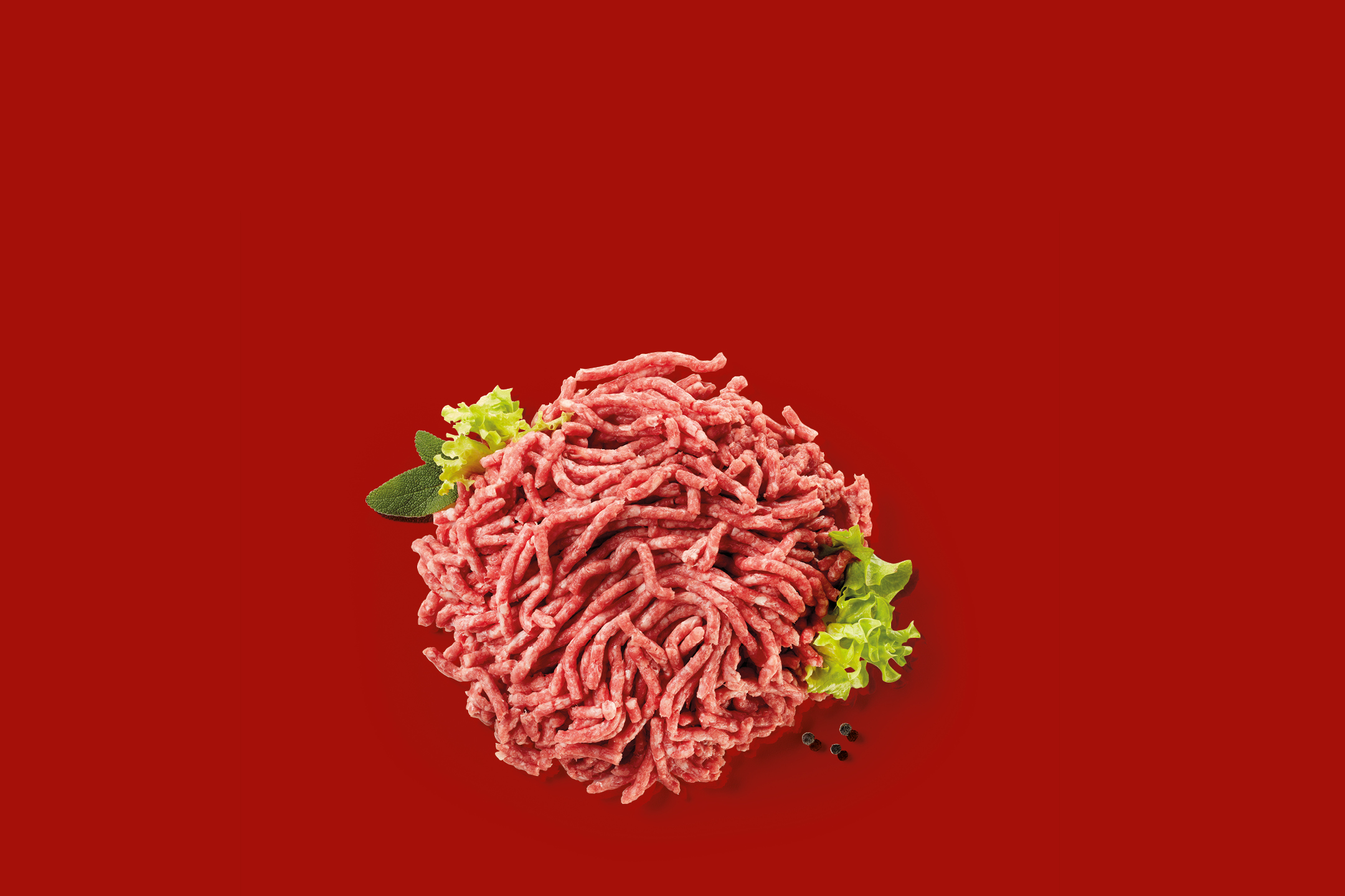 Fresh minced meat with lettuce and peppercorns on a red background.