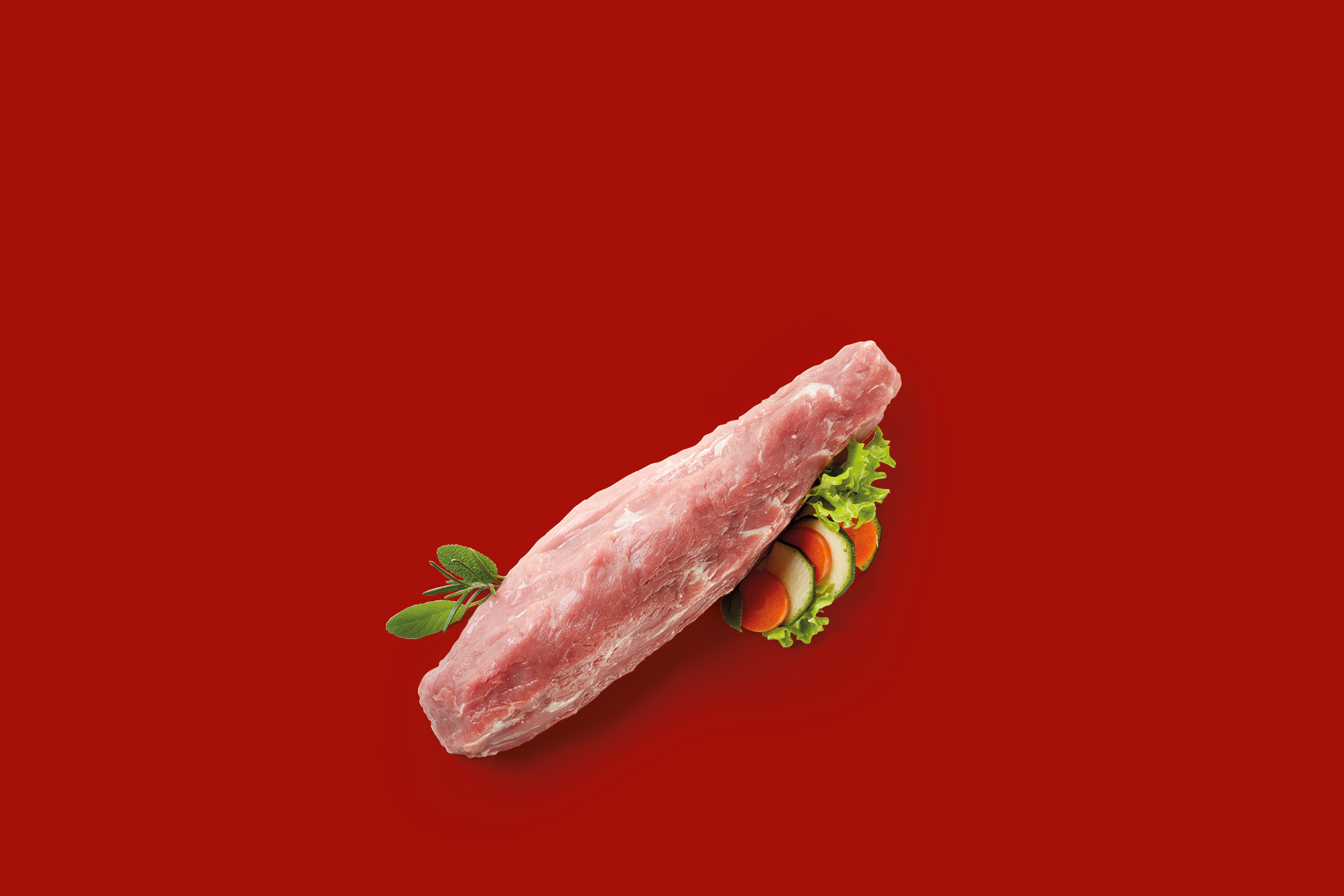 Raw pork tenderloin with fresh herbs and sliced vegetables on a red background