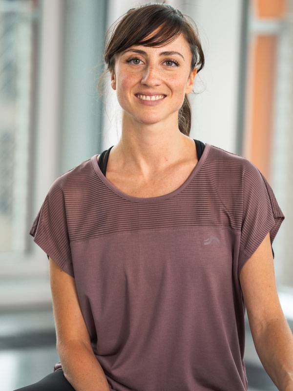 Smiling woman wearing a short-sleeved purple sports top.