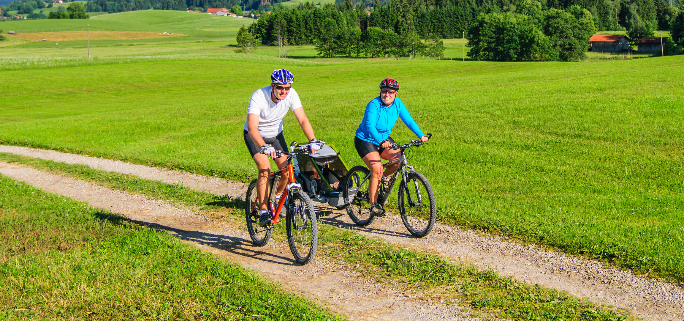 Couple cycling on bikes in a green landscape.