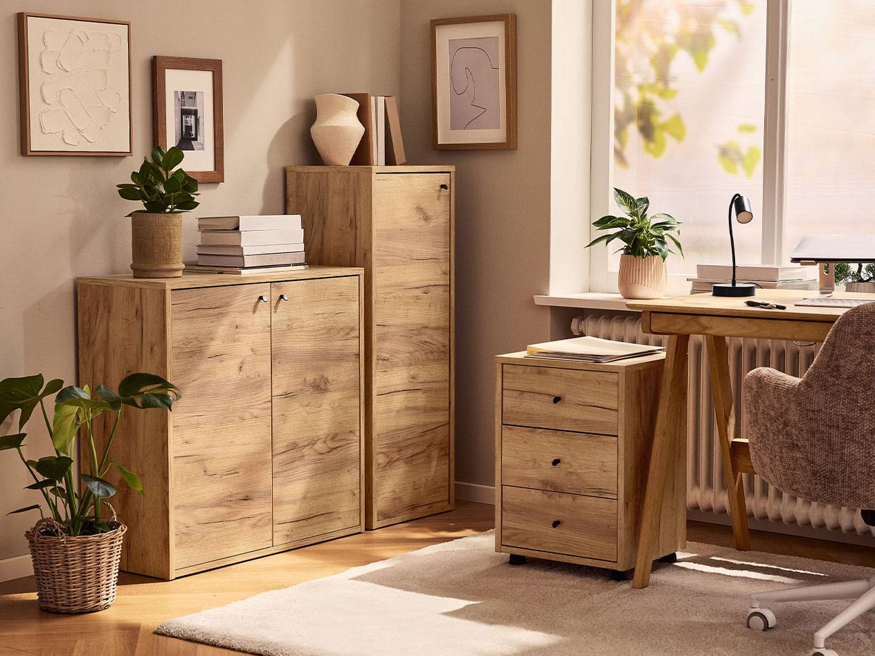 A home office with light wood cabinets, a desk chair, and a desk lamp.