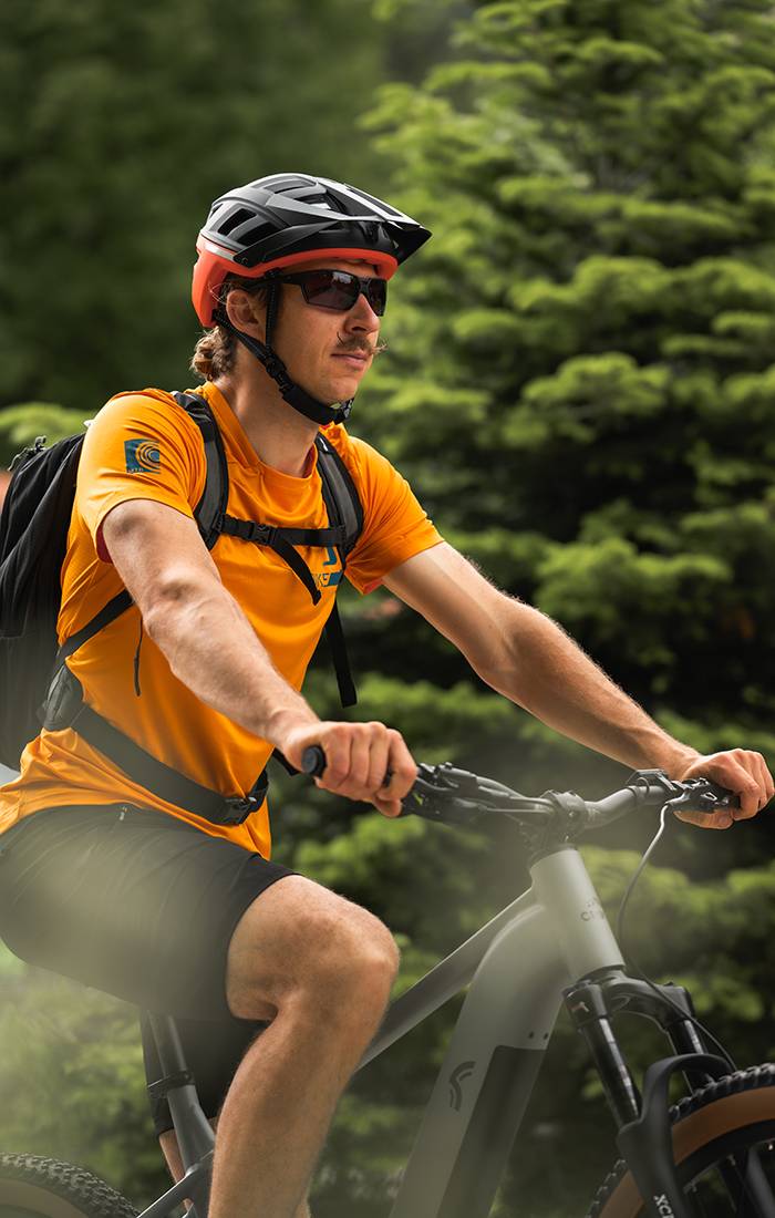 Man riding a mountain bike wearing a helmet and athletic clothing.