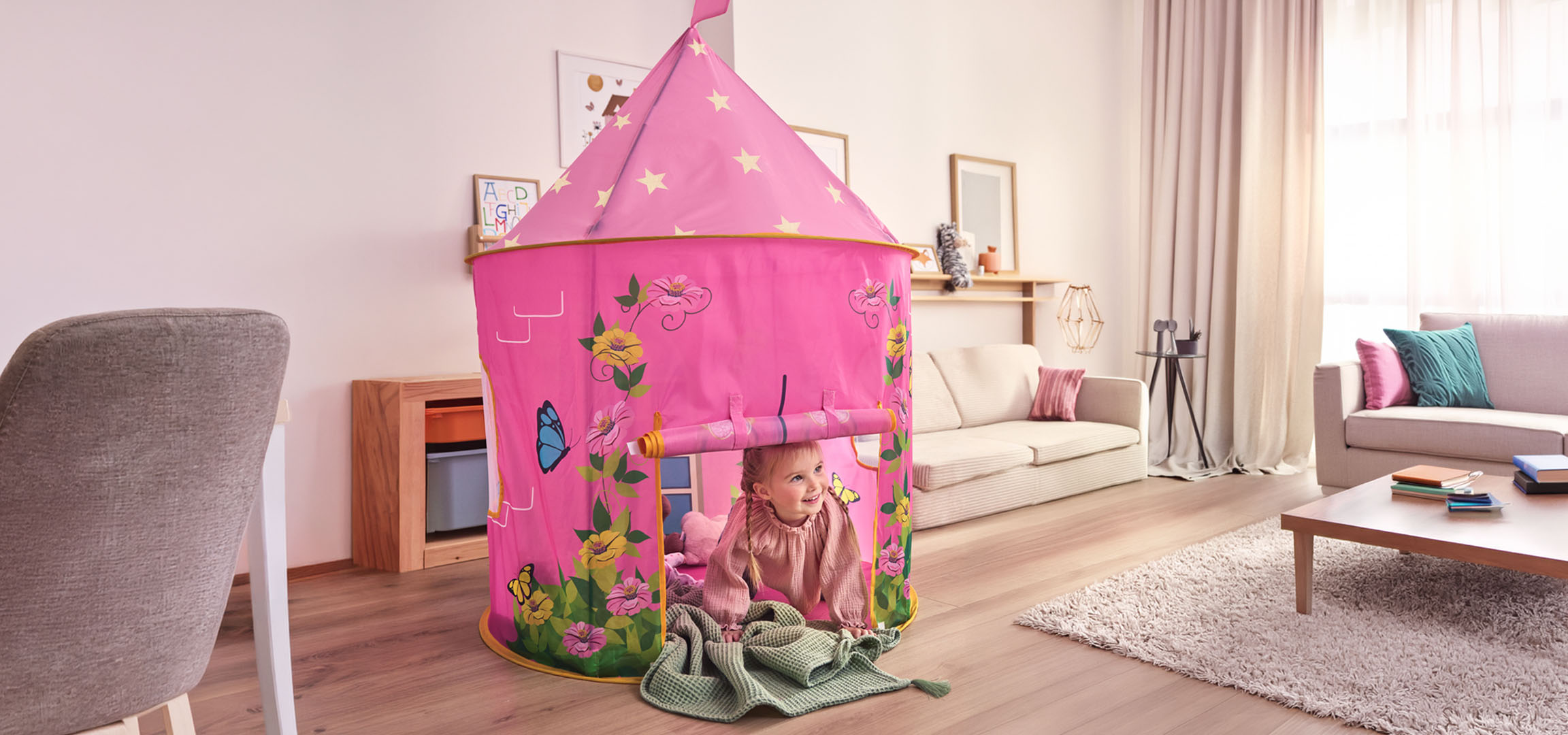 Pink children's play tent in the shape of a castle in a living room with a dining area.
