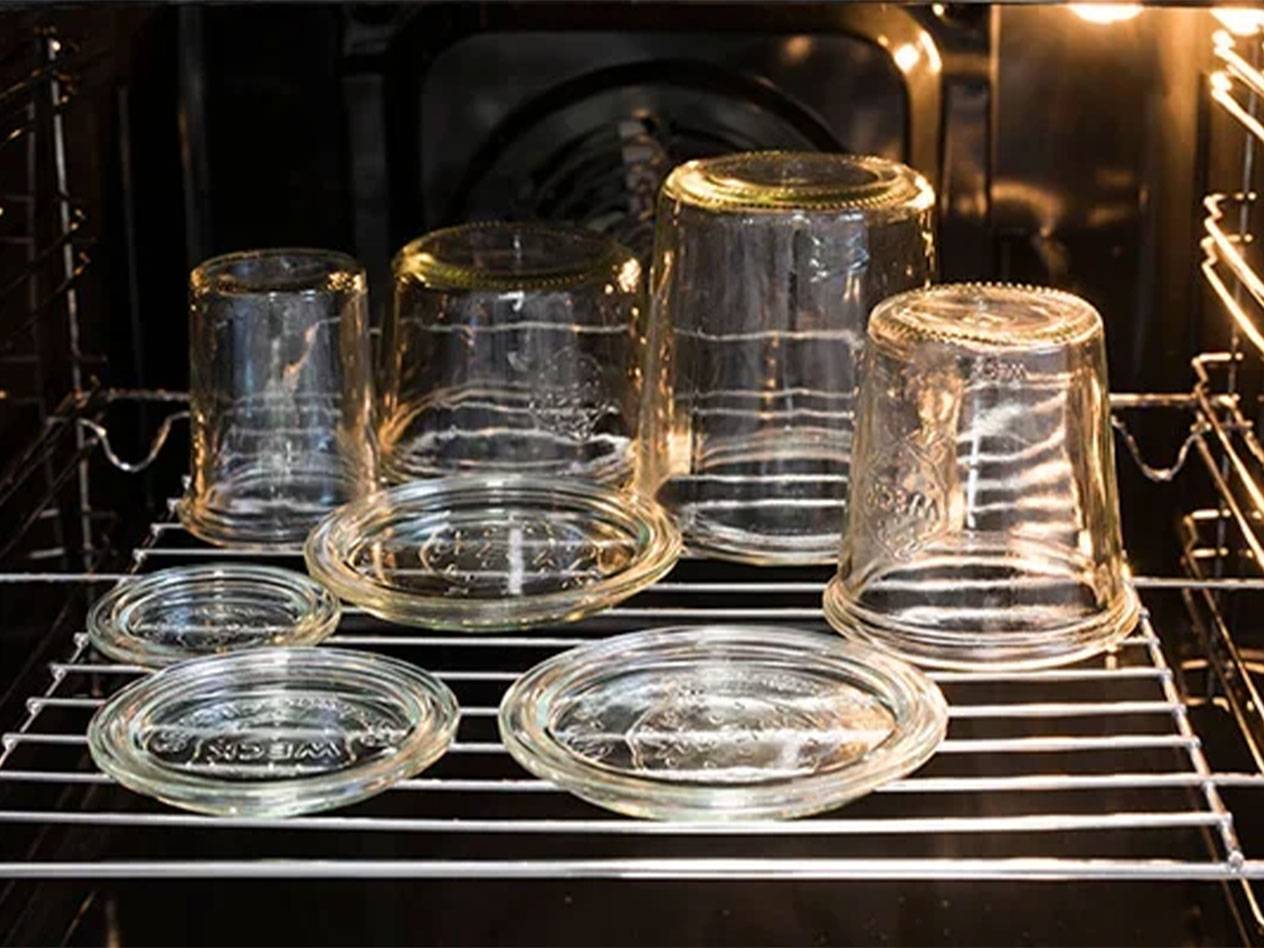 Weck glass jars and lids, placed upside down on an oven rack.